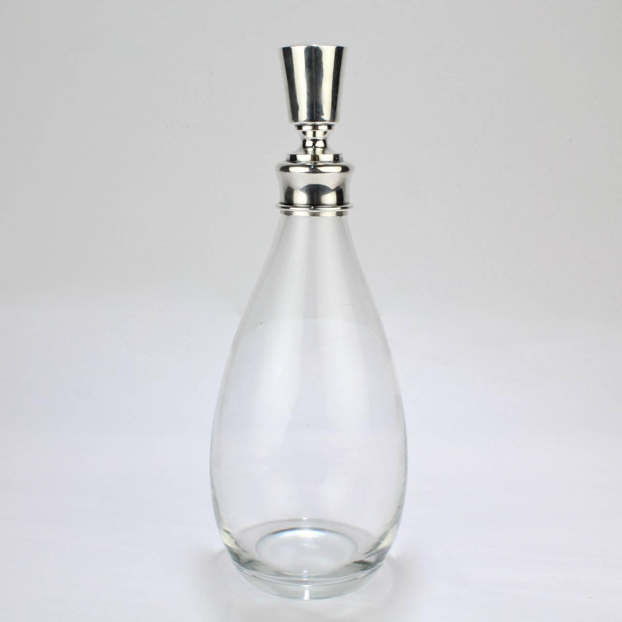 A fine, modernist Hawkes glass and sterling silver mounted decanter or bar bottle.

Stamped Hawkes and Sterling to top and Sterling to bottle's mount. The base bears an acid etched Hawkes factory mark.

Height (inclining top): circa 11