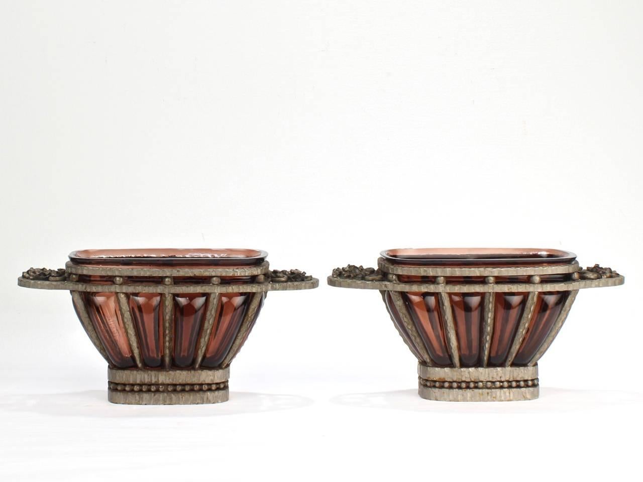 A wonderful pair of Muller Freres art glass and nickel-plated wrought iron cachepots.

Dating to the Art Deco period.

In the style of Edgar Brandt or Louis Majorelle with blown amethyst or purple glass in a wrought iron cachepot or planter