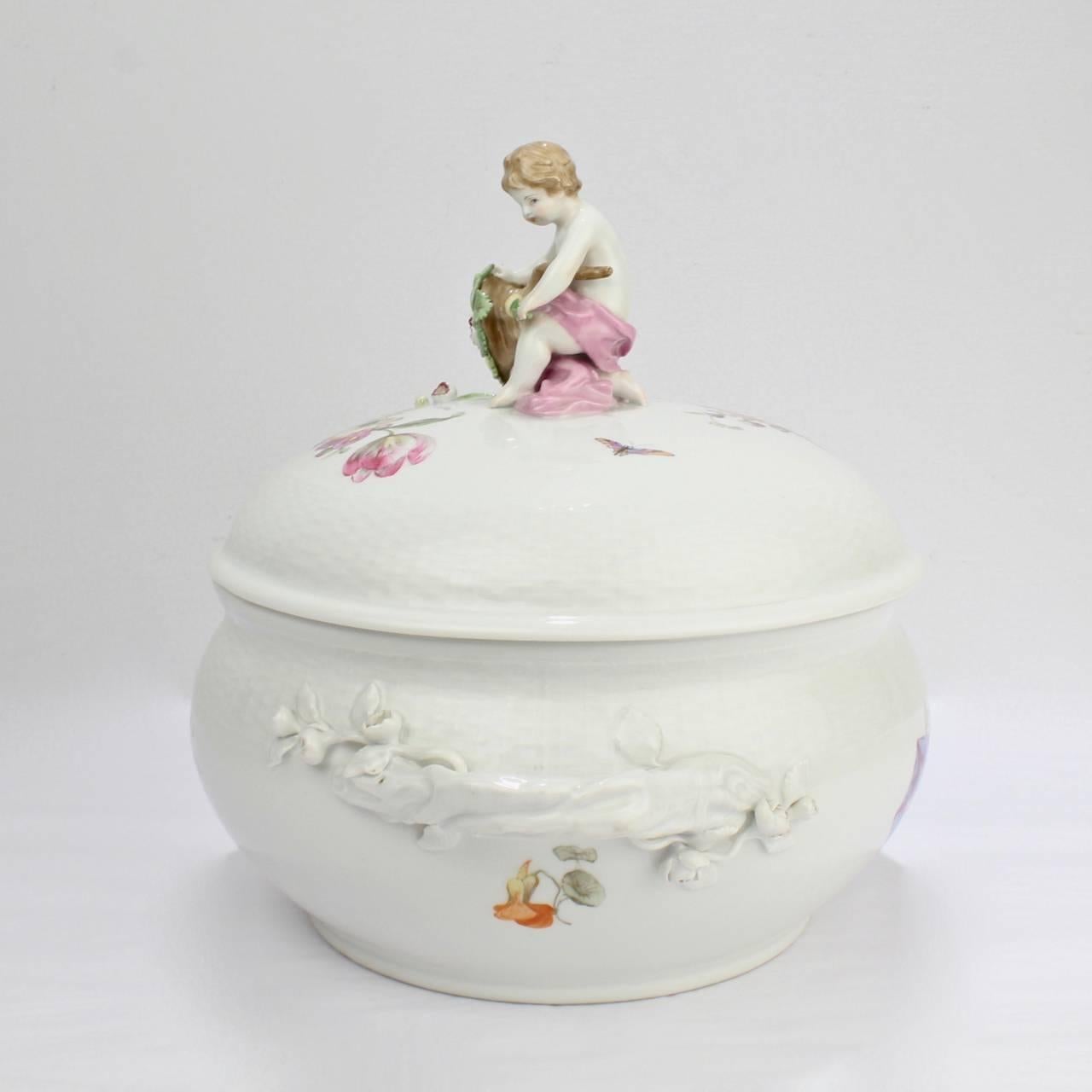 Pregevole zuppiera antica in KPM Porcelain con manici incrostati di fiori, spruzzi floreali Deutsche Blumen e finale figurato con cherubino e cornucopia. 

La base reca il marchio dello scettro di fabbrica blu sottosmalto, il marchio del globo di