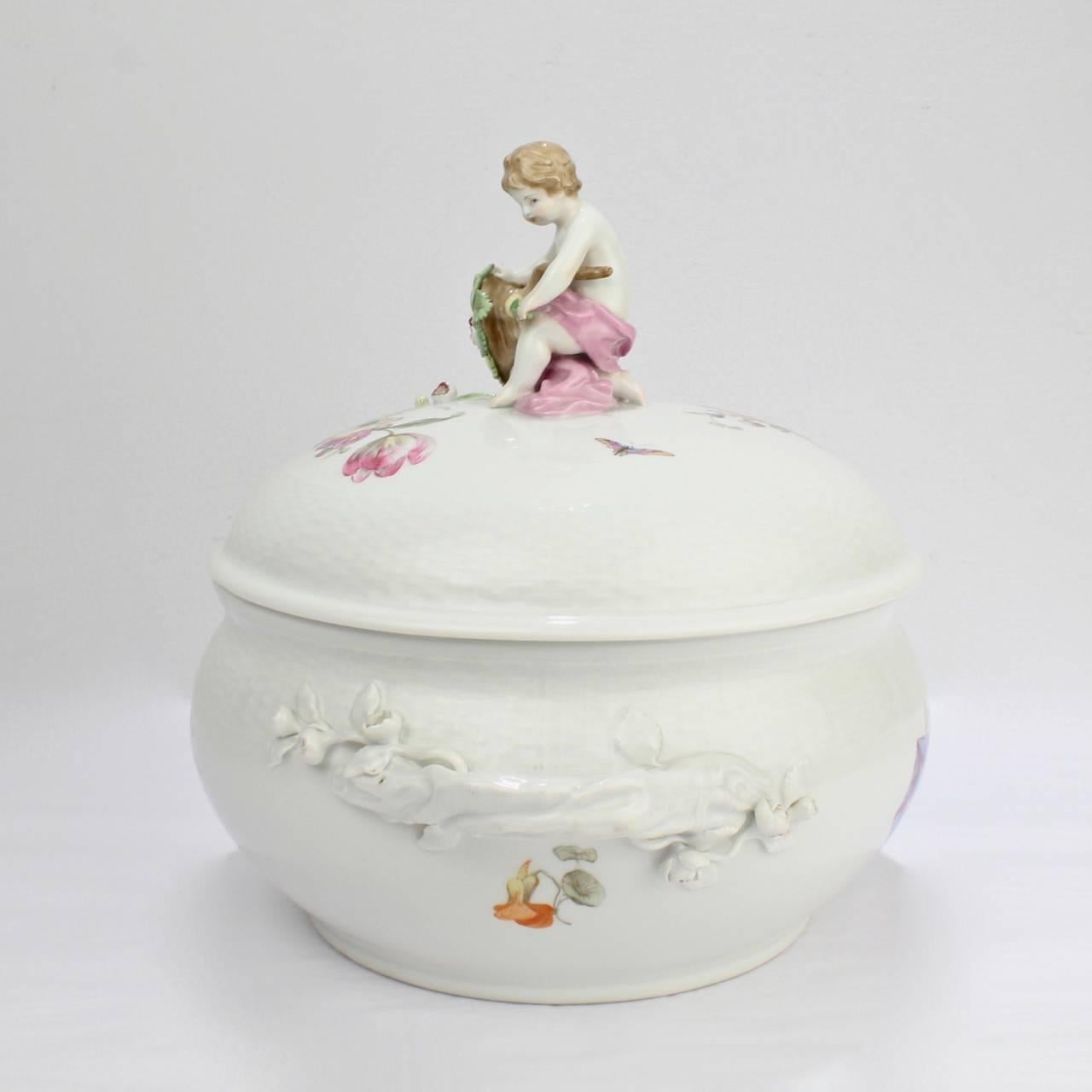 Une belle soupière ancienne en porcelaine KPM avec des poignées incrustées de fleurs, des gerbes florales Deutsche Blumen, et un chérubin figuratif et une corne d'abondance en guise de fleuron. 

La base porte une marque de sceptre d'usine bleu