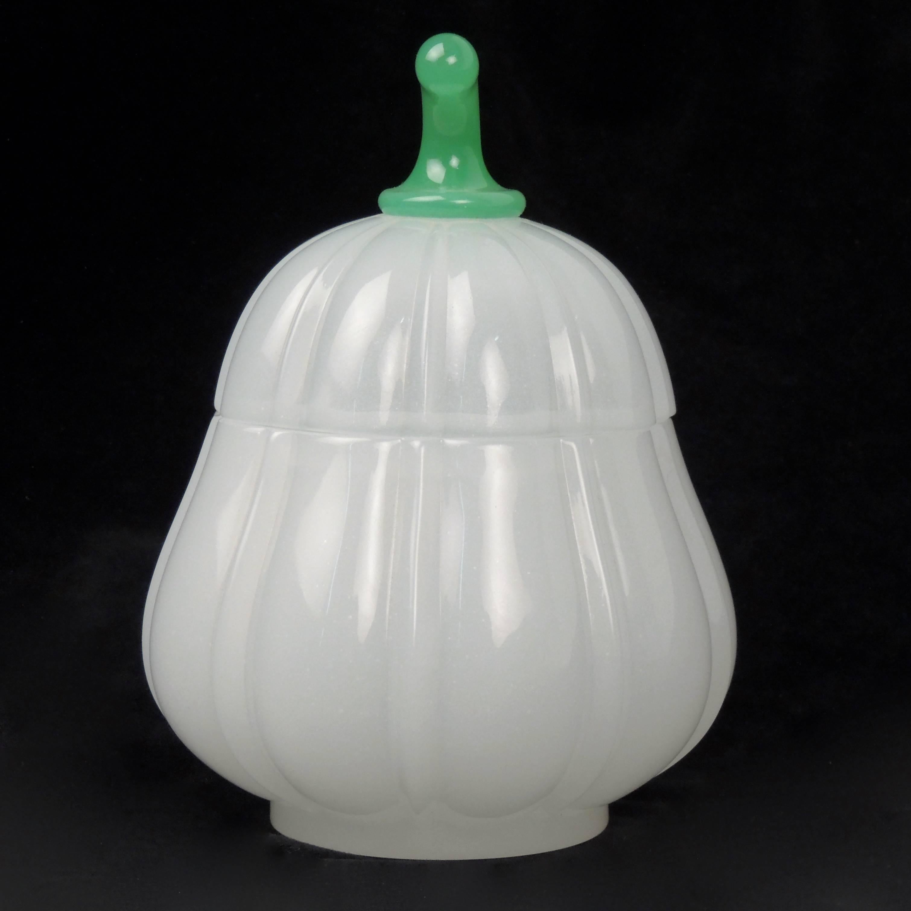 An opaline glass pear-shaped dresser jar or lidded box. Made by Baccarat.

The fluted body has a conforming lid with a green opaline glass finial. The glass has fine bubbles throughout. (See our close up image for details.)

The base bears an