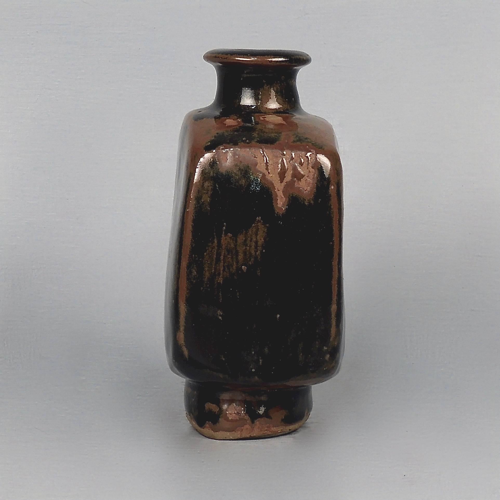 A handsome tenmuko glaze square stoneware bottle or vase by Bernard Leach (1887-1979). 

The base bears impressed marks for Bernard Leach, the St. Ives, and England. 

There are wonderful glaze skips to the shoulders and foot and the side has an