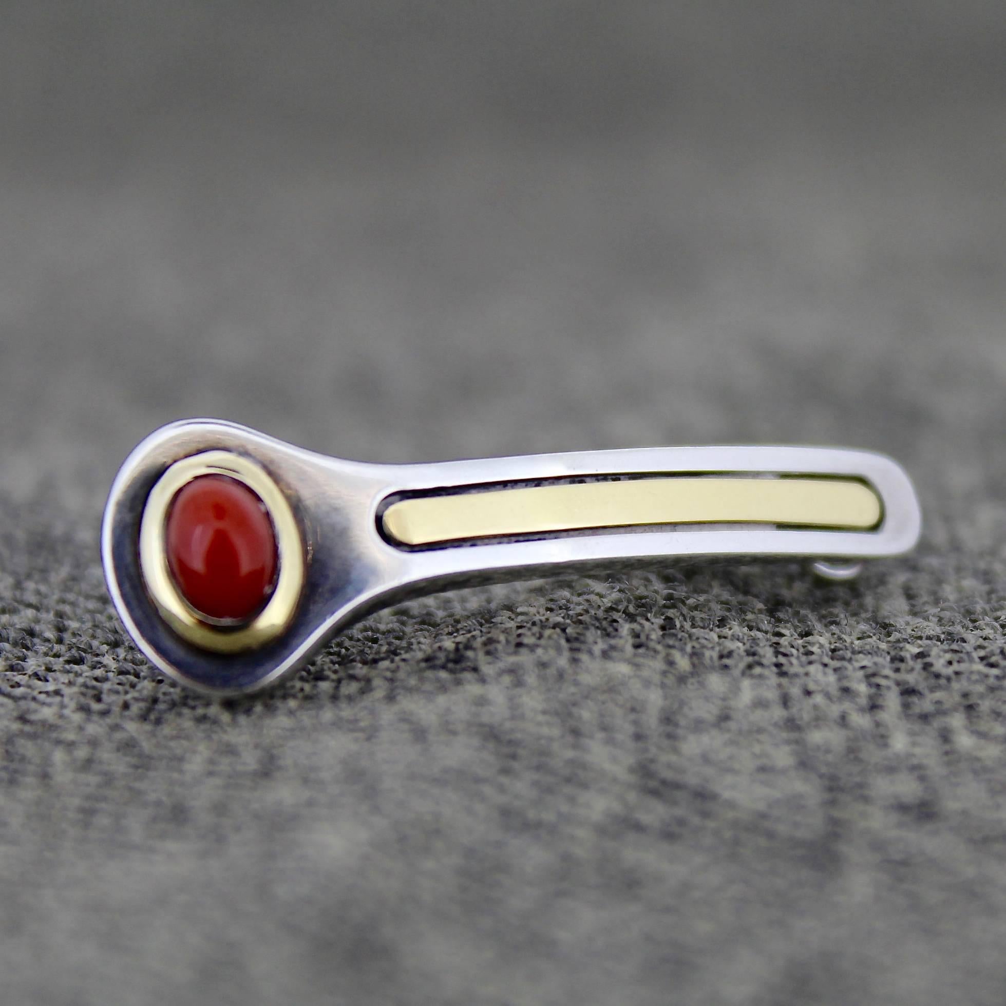 A wonderful, vintage, signed Cartier lapel pin or brooch. This pin simply embodies modern design. Constructed of sterling silver and 18-karat yellow gold, it has red coral cabochon at the end.

 It is marked 