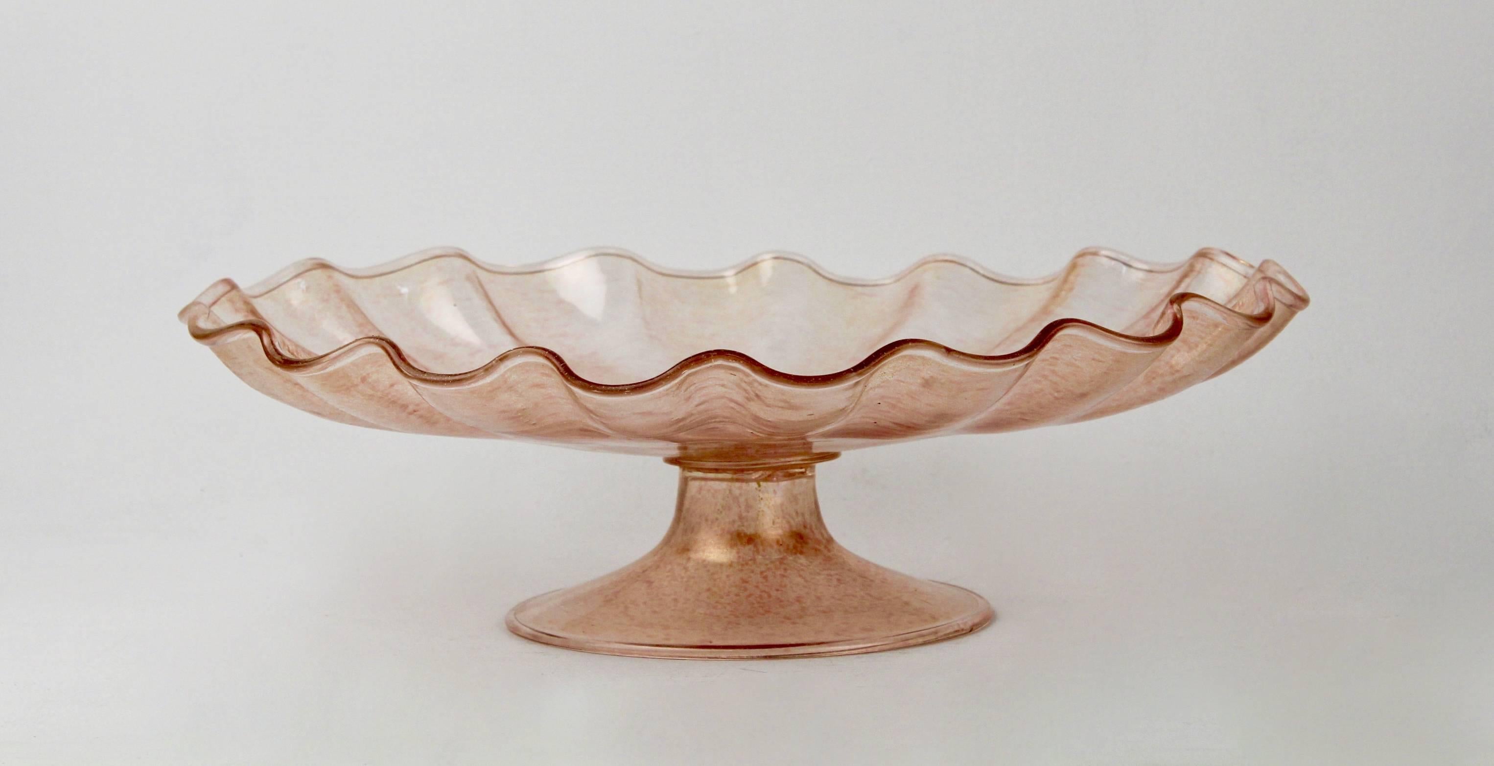 A large and decorative vintage pink Murano glass with gold foil footed stand or tazza. Probably by Salviati.

Width: circa 16.75 in. 

Items purchased from David Sterner Antiques must delight you. Purchases may be returned for any reason for a