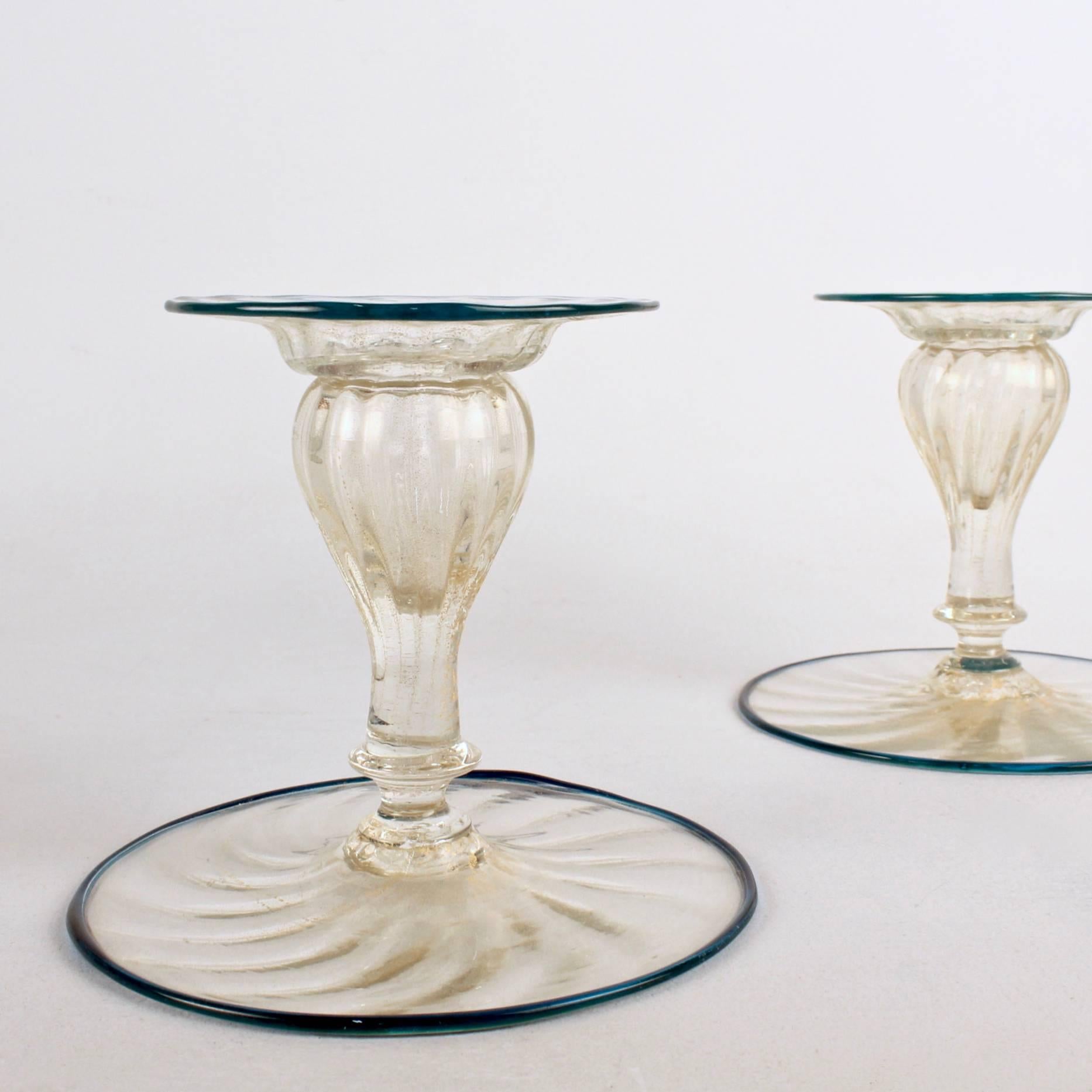 A set of four Venetian glass candlesticks. 

They consist of light amber glass with gold fleck inclusions with a left handed swirl and applied teal ribbon edges. Each has a matching, removable bobeche. A real rarity. 

Likely Pauly or