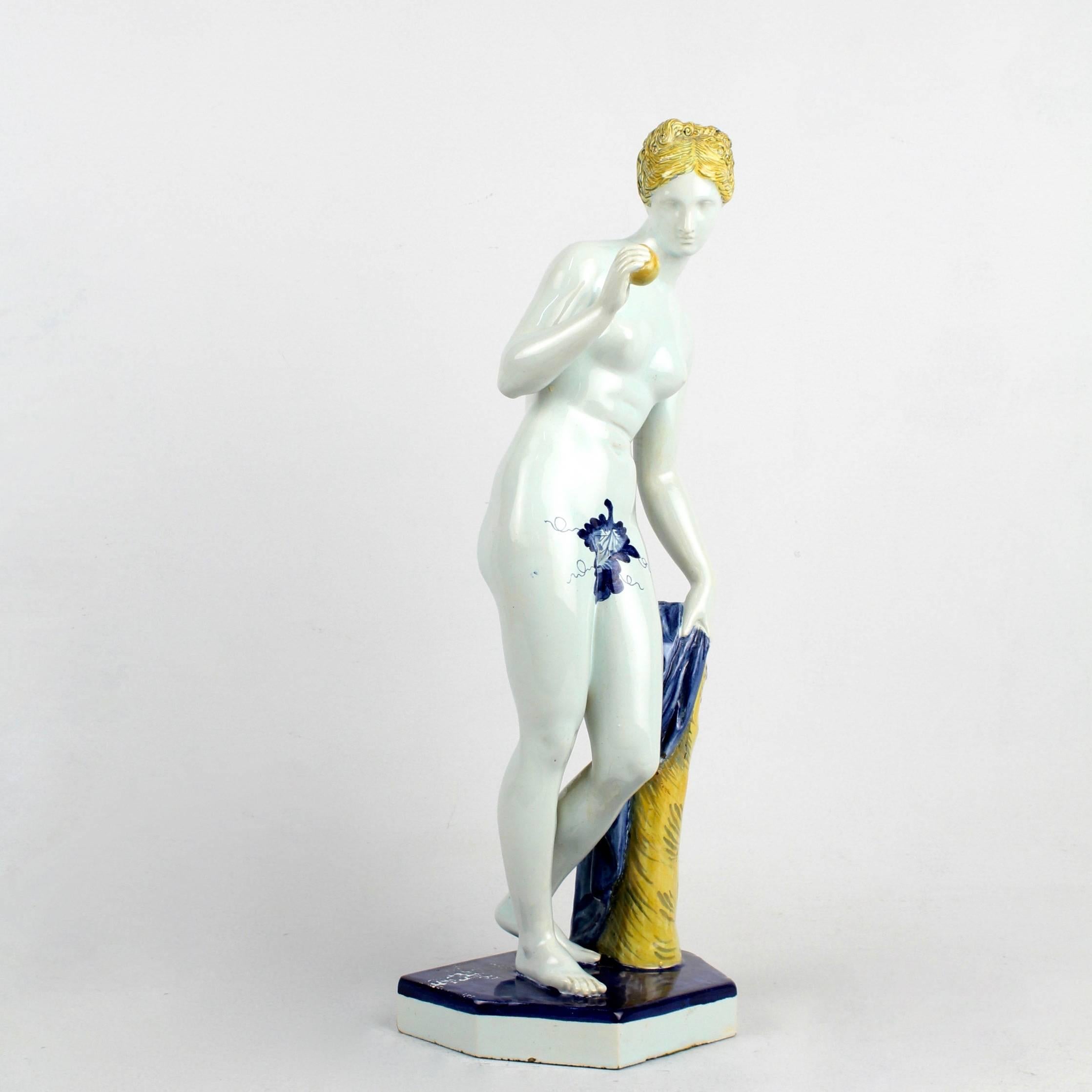 A large 19th century Samson et Cie faience figurine depicting either Venus & the Golden Apple or a rendition of Eve with the Apple. We seen this figure called both.

This nude Venus or Eve figure stands on a hexagonal base next to a tree trunk. In