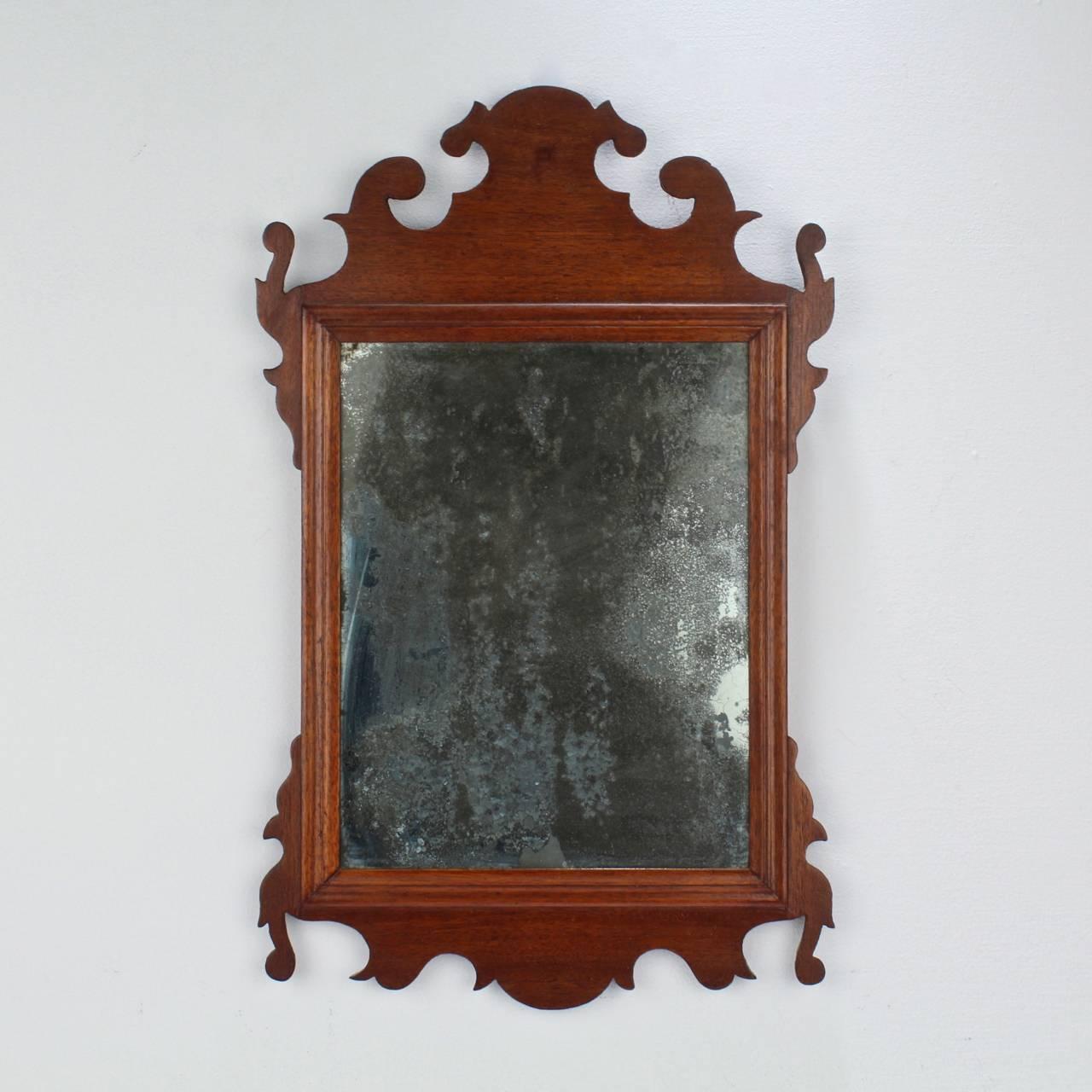 A Fine and diminutive period Chippendale mahogany mirror or looking glass. 

American or English.

Found just outside Philadelphia. 

Retains an old glass with losses to much of the original silvering.

Measures: Height ca. 18 in.

Items