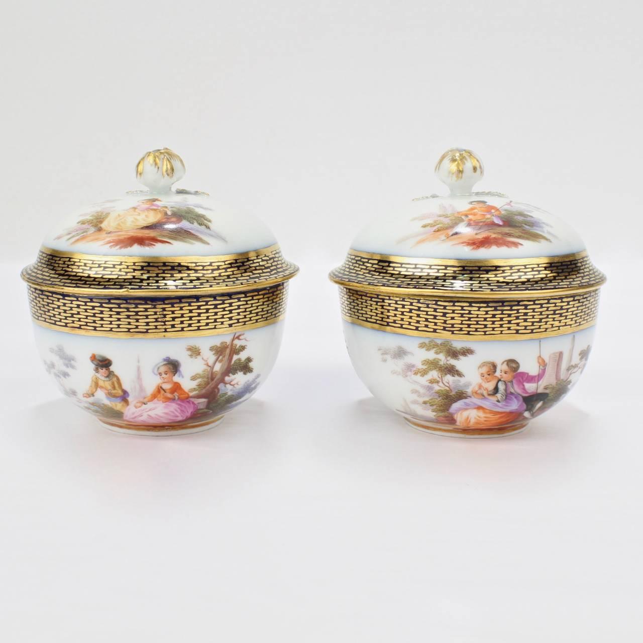A very fine, matched pair of 19th century Meissen covered tea cups and saucers (or demitasse coffee cups and saucers.)

With wonderful hand-painted scenes of lovers to the lids, cups, and saucers. The rims decorated in underglaze cobalt blue and