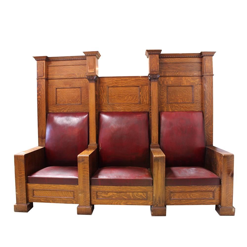 These massive statement pieces are substantial in their heft and presence. Made of solid quarter-sawn oak, these three-seat bench thrones were salvaged from the fraternal lodge for which they were custom made in the early 20th century. Leather seats