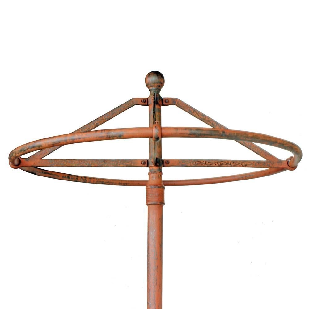A classic Victorian era cast iron clothing rounder complete with casters. A delicate curlicue pattern has been cast into the upper bars and the deep orange paint has just the right amount of weathering.