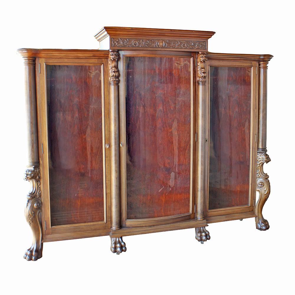 Beautiful hand-carved details on this early 20th century curio cabinet make for a stunning storage piece. Crafted of solid walnut, there is a wealth of beautifully crafted relief and dimensional carving; roaring lions accent the front columns and