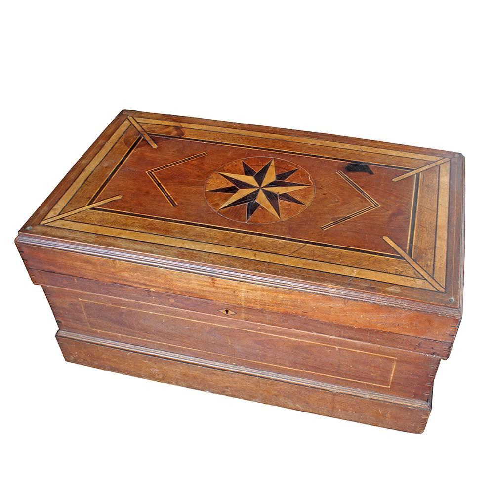 This skillfully handcrafted trunk was made in the early 20th century. Beautiful marquetry work abounds on this piece, seen even in the dovetailing of the joints. The interior lid of the chest is emblazoned with a masonic symbol and the letter “G” at