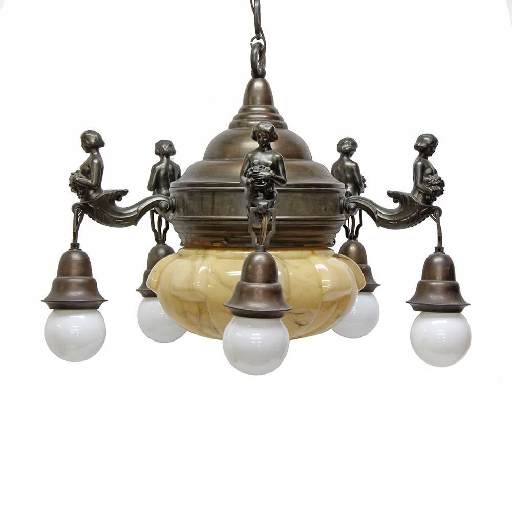 This beautiful early 20th century chandelier has a unique beauty in both its form and decoration. Five hanging pendant bulbs are suspended from cast bronze mermaids and a central fixture is encased behind a faux alabaster glass shade. Though the
