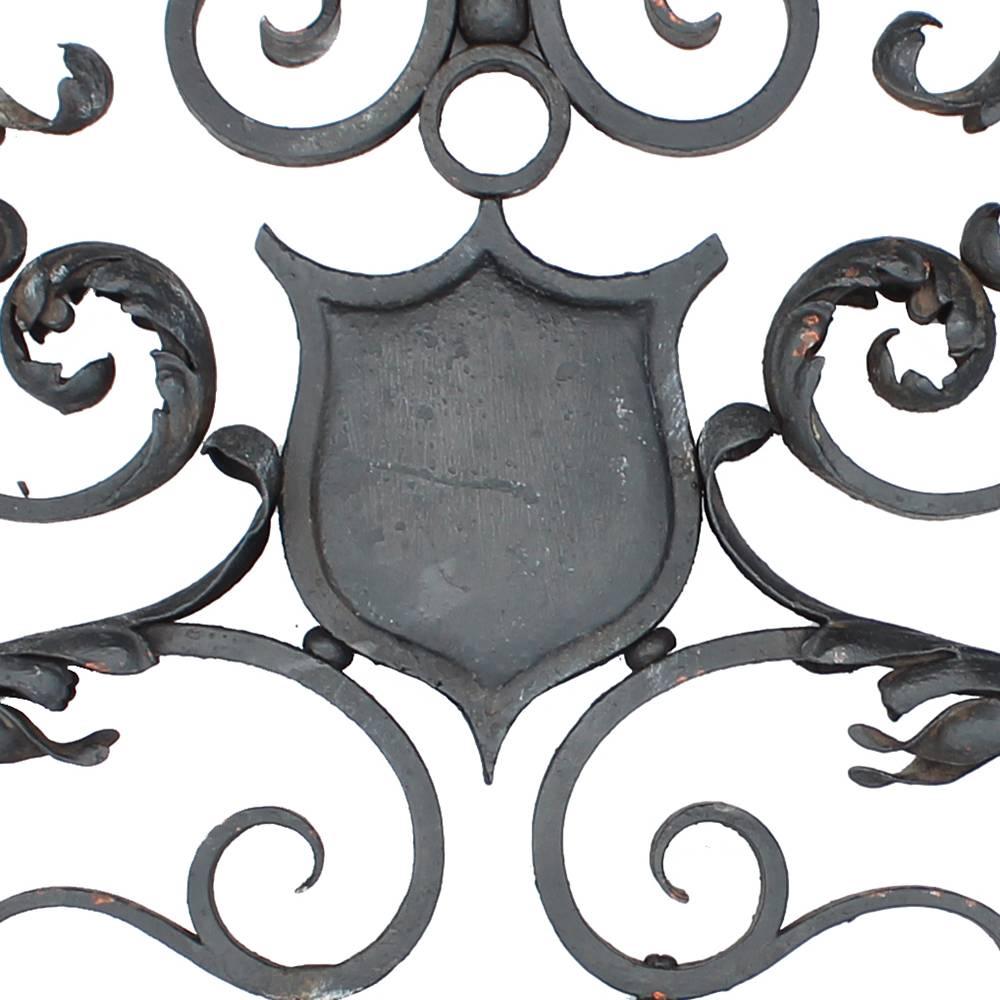 Graceful and beautiful execution on this stunning late Victorian era fence header. Made from cast and wrought iron elements, this unique piece features delicately sculpted curling vegetation adorning the elaborate scrollwork. A central plaque could
