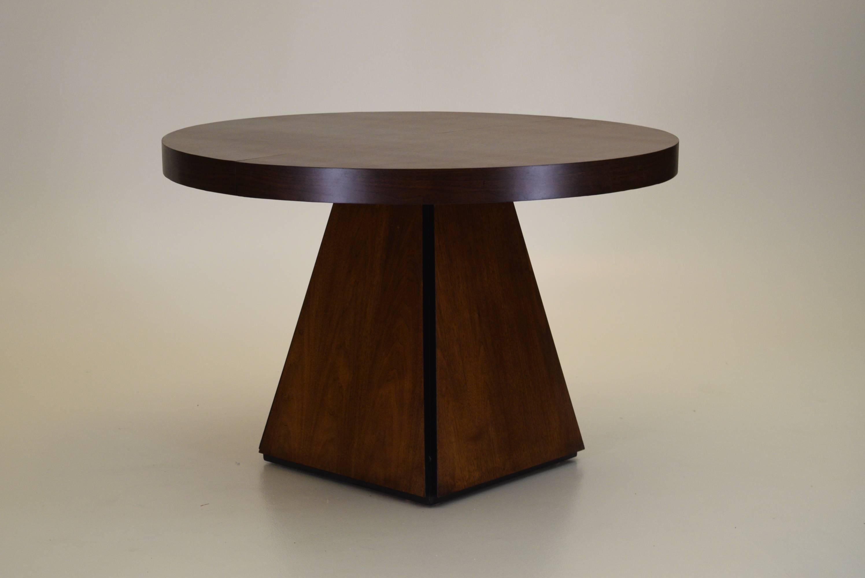 A very rare model dining table designed by Pierre Cardin as part of a line for Dillingham furniture.

In addition to this, the original single leaf is also present. 

The obelisk style base features recessed corners and a lip that allows the