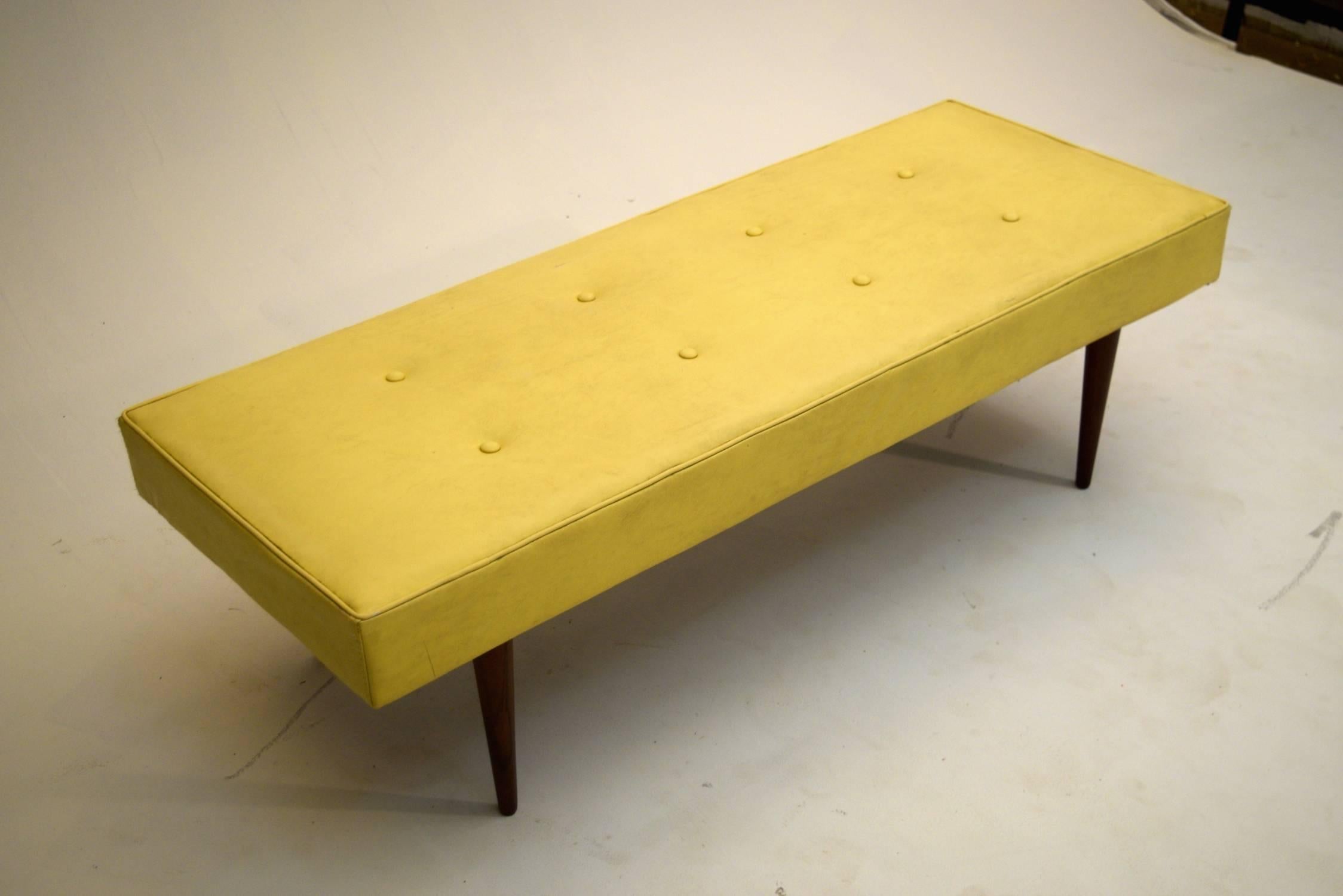Sturdy bench produced with solid walnut legs, tufted vinyl with lasagne spring construction.  Good design with quality construction that could easily be reupholstered in any desired color and fabric, including this original sunny yellow vinyl.  