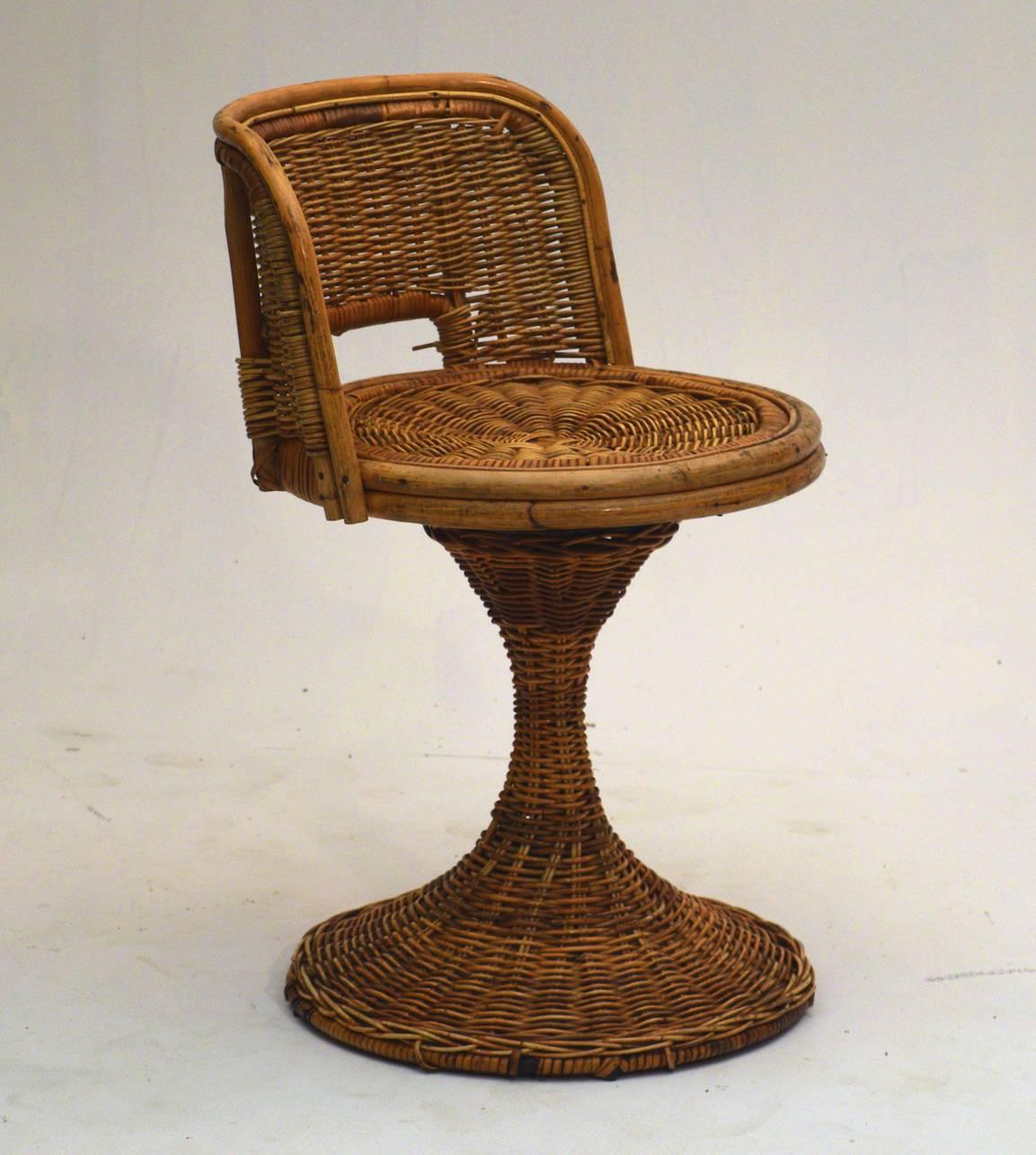 In the manner of Franco Albini, circa 1955 is a dining table and two tiki swivel chairs in wicker rattan.  Measures: Table 28