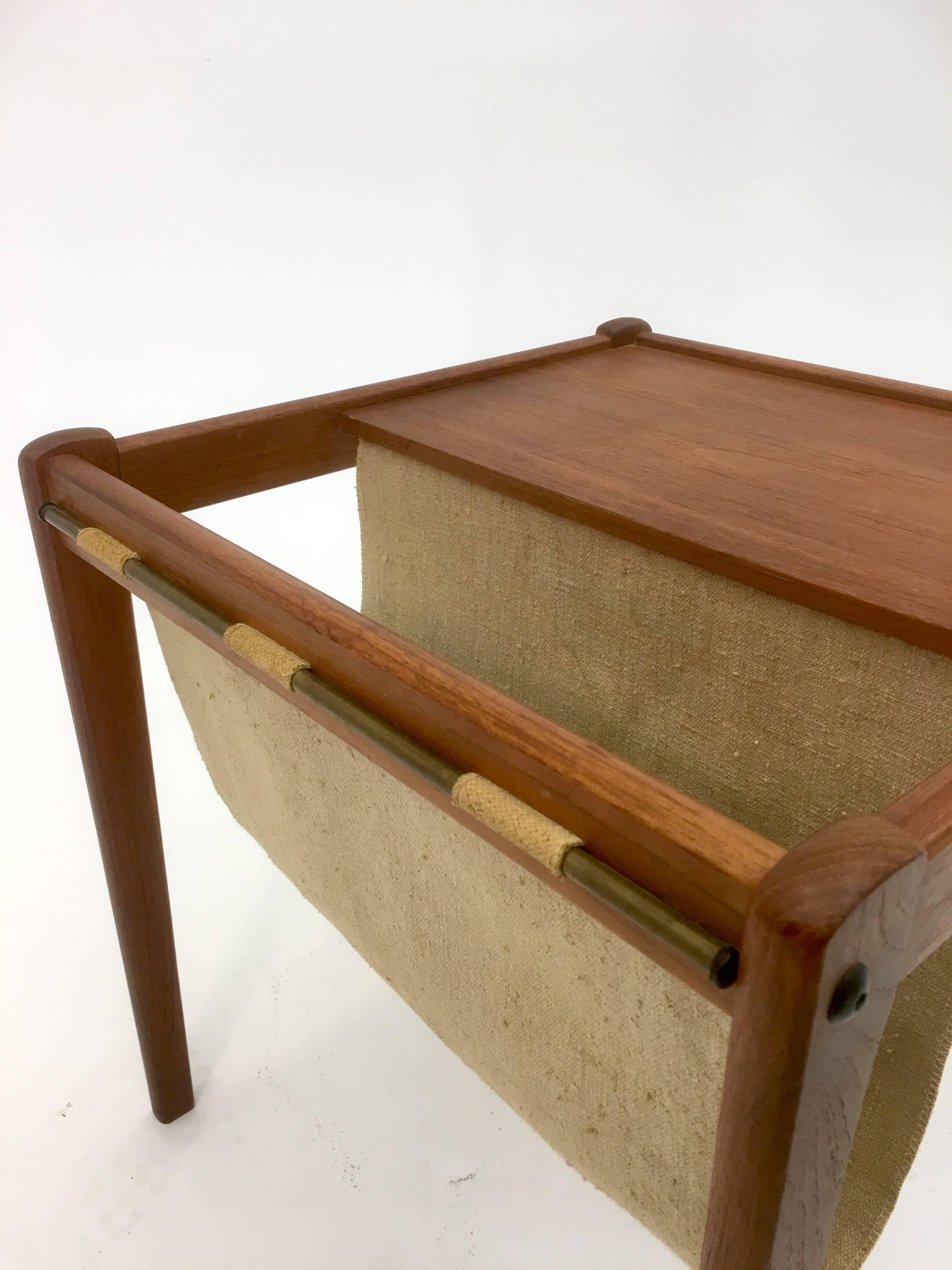 Made in Denmark by the company BRDR Furbo Stottrup, circa 1965. Solid teak construction with Danish canvas used in a sling form to hold magazines and other articles. 

A bras bar holds the canvas in place. Perfect for a hallway or when a table is