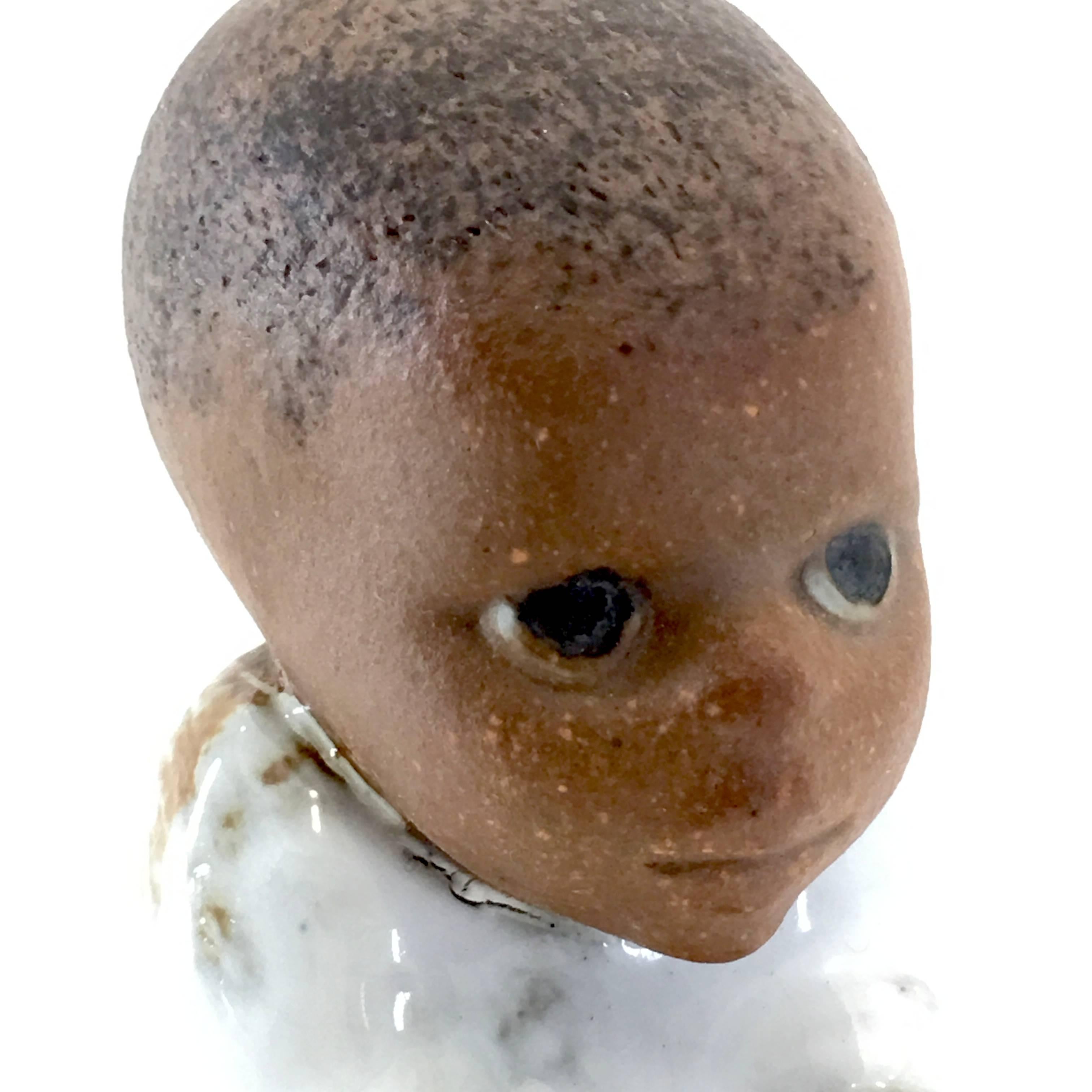 Produced in 1974 by Lisa Larson of Sweden as part of the children of the world series. Negro boy in sitting position. Material is pottery with glaze.

Measures: 4