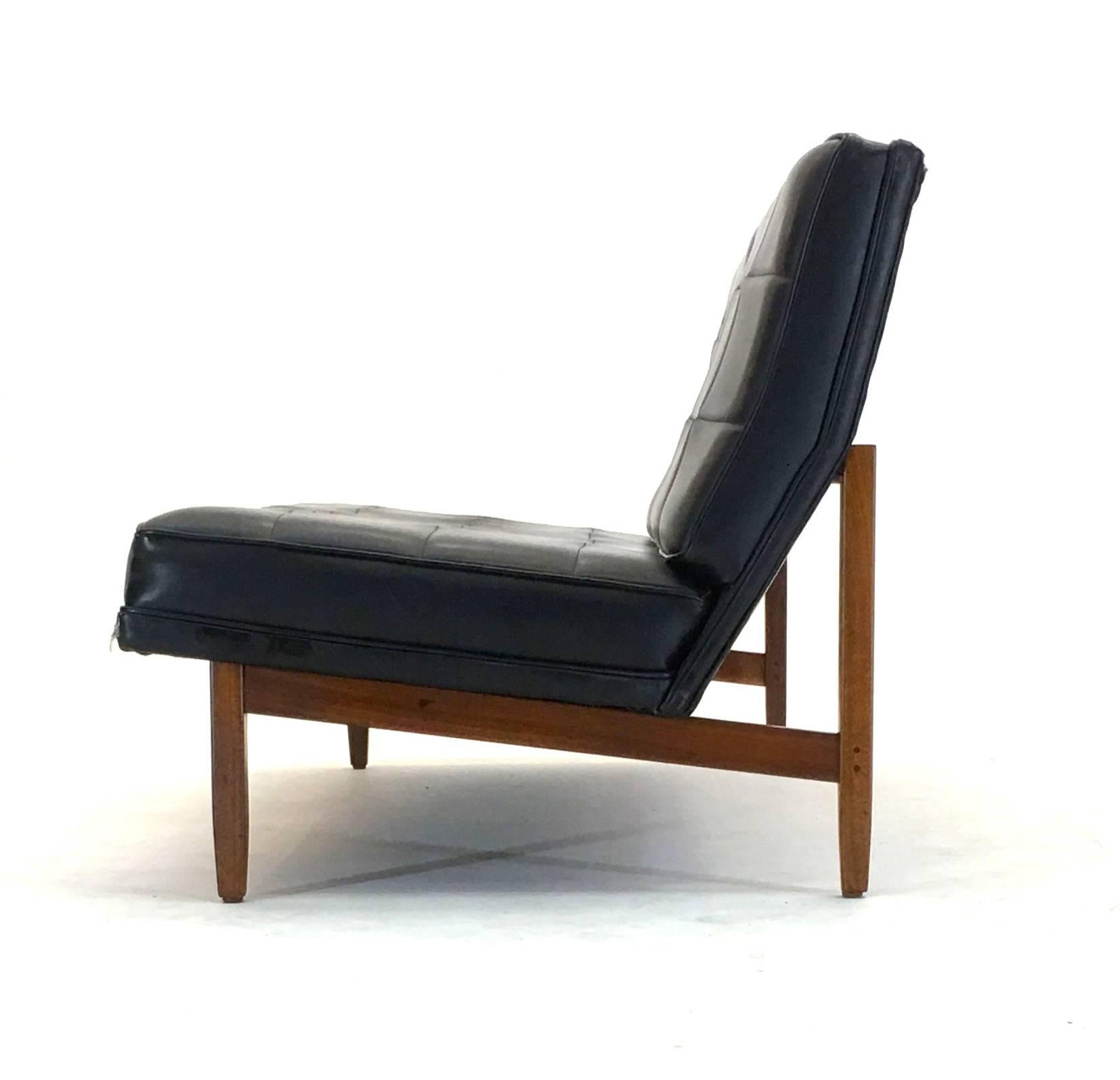 Put into production in 1952, this armless sofa by Florence Knoll is a first year production piece. Features a walnut frame that has been refinished and is in excellent condition. Due to the condition of the black vinyl, this article has been priced