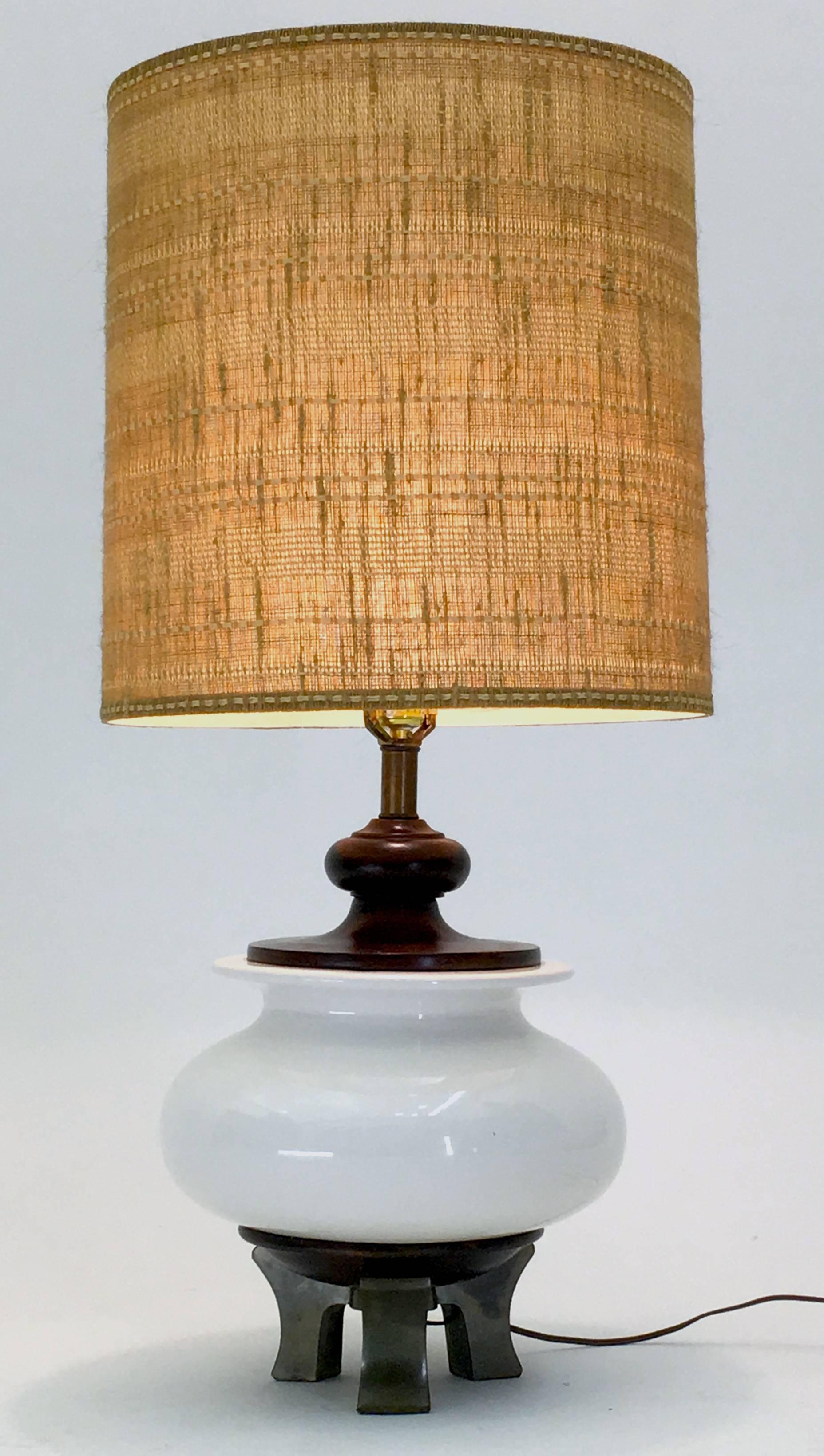 A very large bulbous ceramic vessel of 14" diameter upon a tripod or three legged base of brass designed and produced by Morris Greenspan. This is a unique lamp with beautiful wood accents to the top and bottom and with its lovely white glaze
