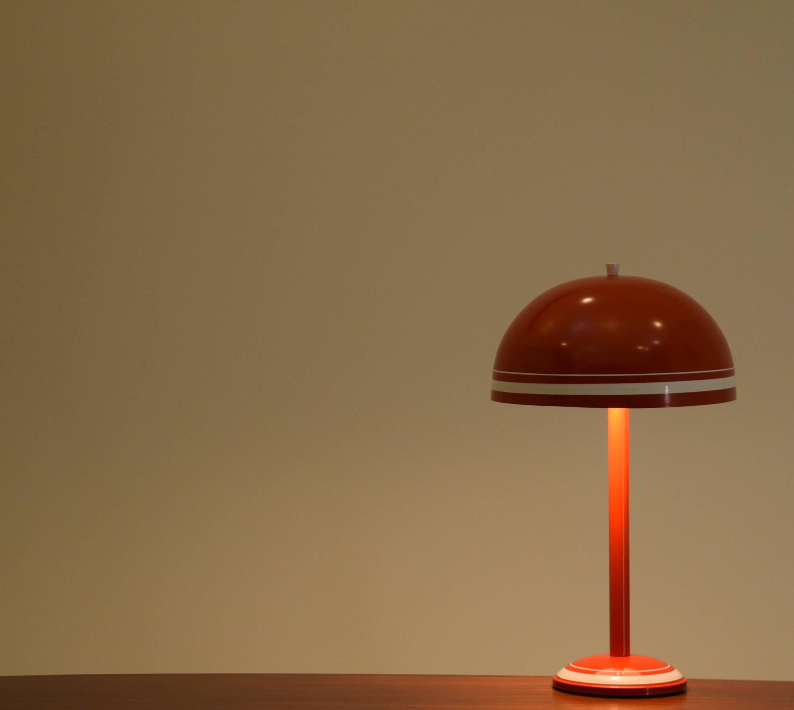 An all-steel construction mushroom lamp from the 1970s. Has two power sockets located below the mushroom shade. On/off power switch located on cord. In brilliant red with white strips. In excellent condition. 

Manufacturer unknown though it is