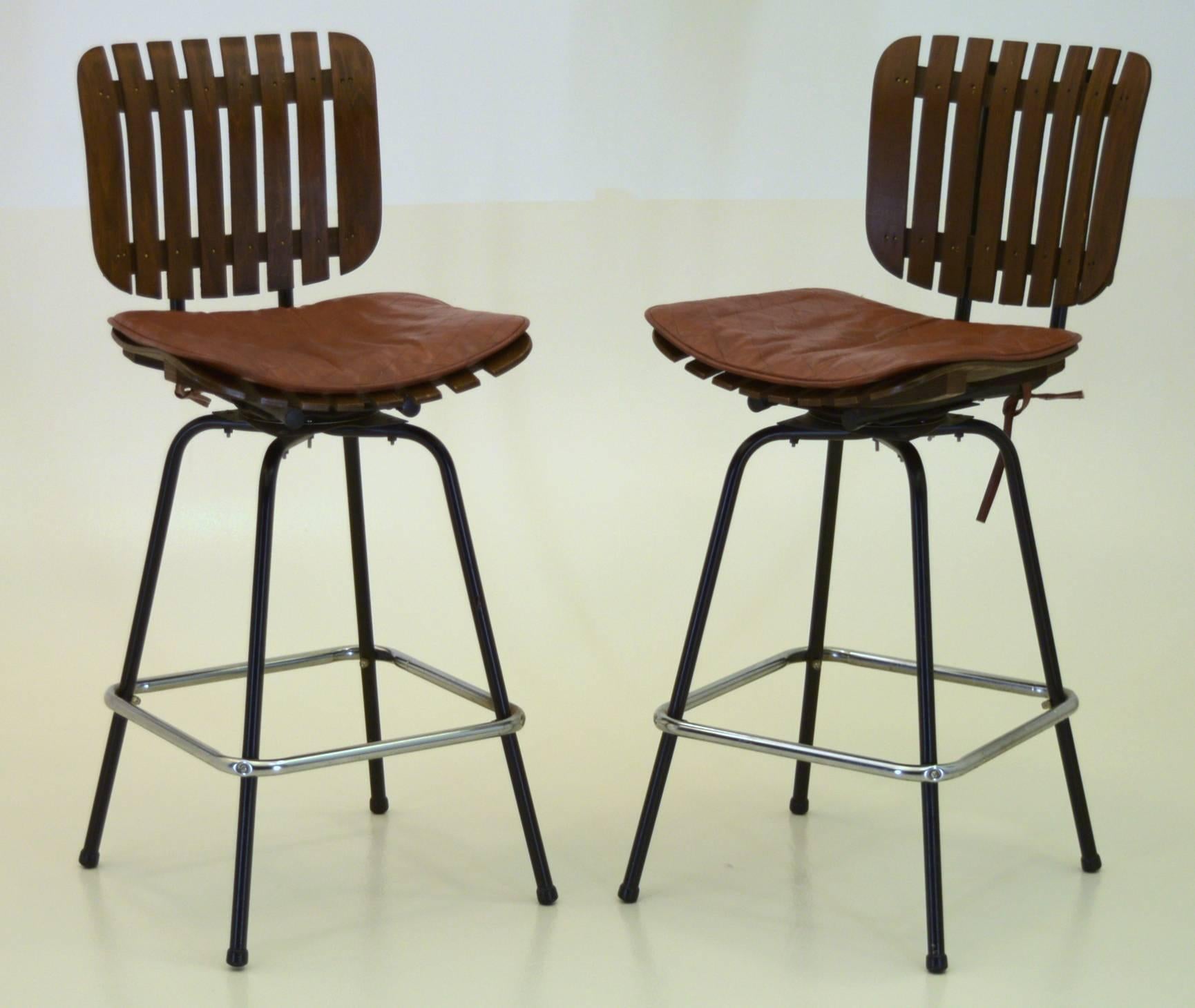 A beautiful trio of well cared for slat bar stools with solid steel frames. This set of three bar stools are in excellent condition and have been very well cared for. The seats come with leather cushions in patchwork that are very practical.

They