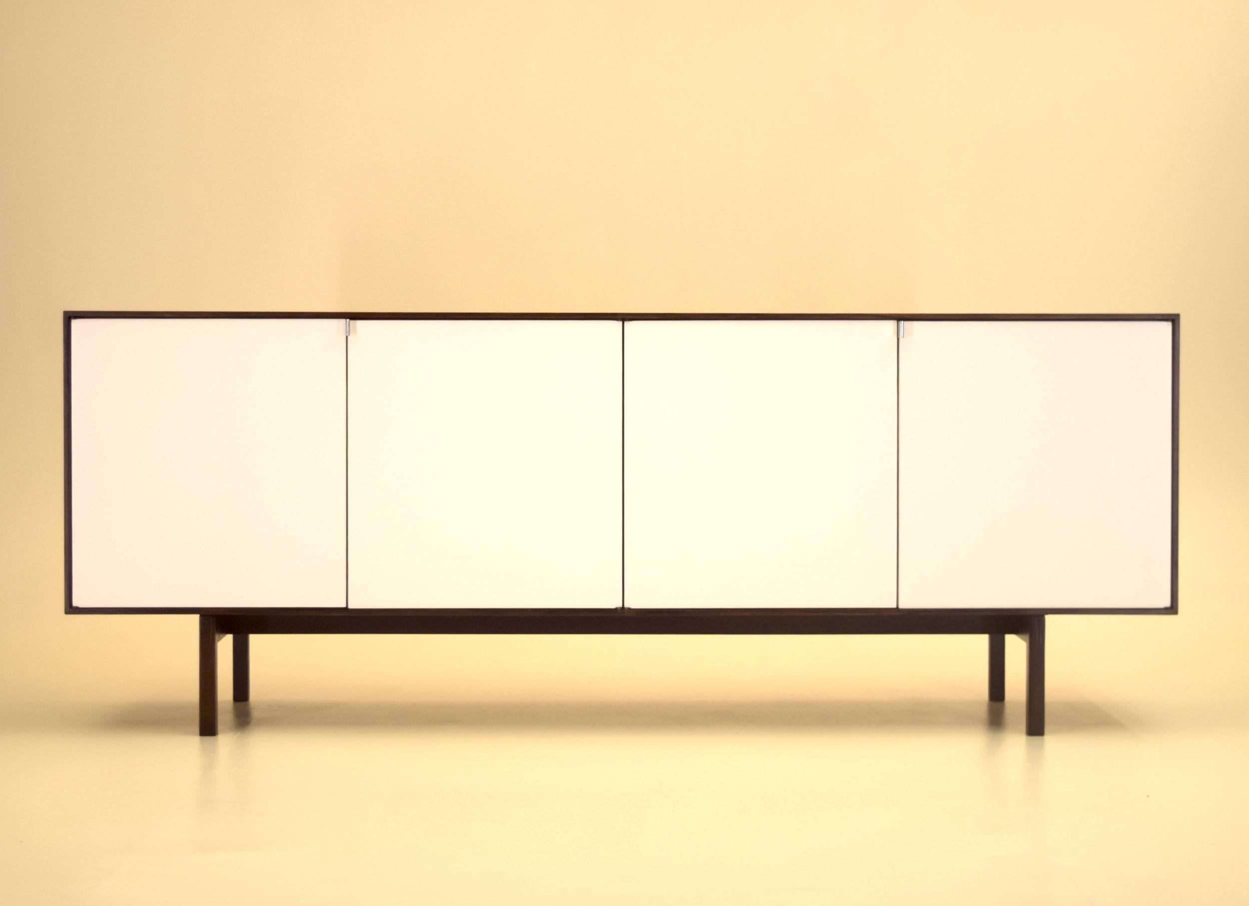 Vintage - though nearly like new, this sideboard features white lacquered doors as well lacquer to interior which was only executed on the rosewood models. Featuring as well mortised rosewood base and chrome pulls, circa 1958-1962.

This model and