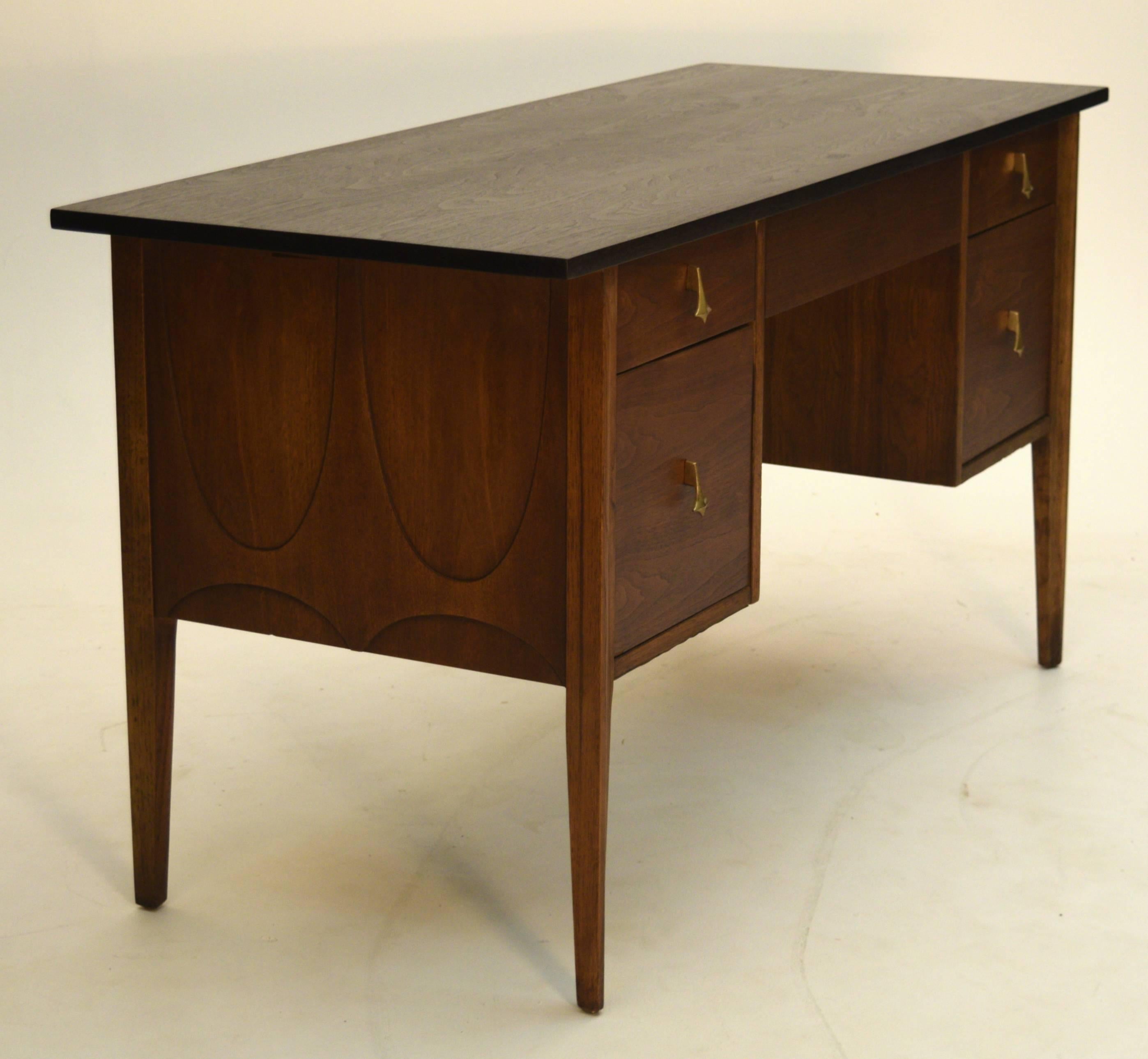 A beautiful walnut desk by the Broyhill company from their Brasilia Premier line featuring a central finger pull drawer, 2 pencil drawers as well 2 file drawers. Complete with vanity screen in rattan and the Classic Oscar Niemeyer pattern the sides.