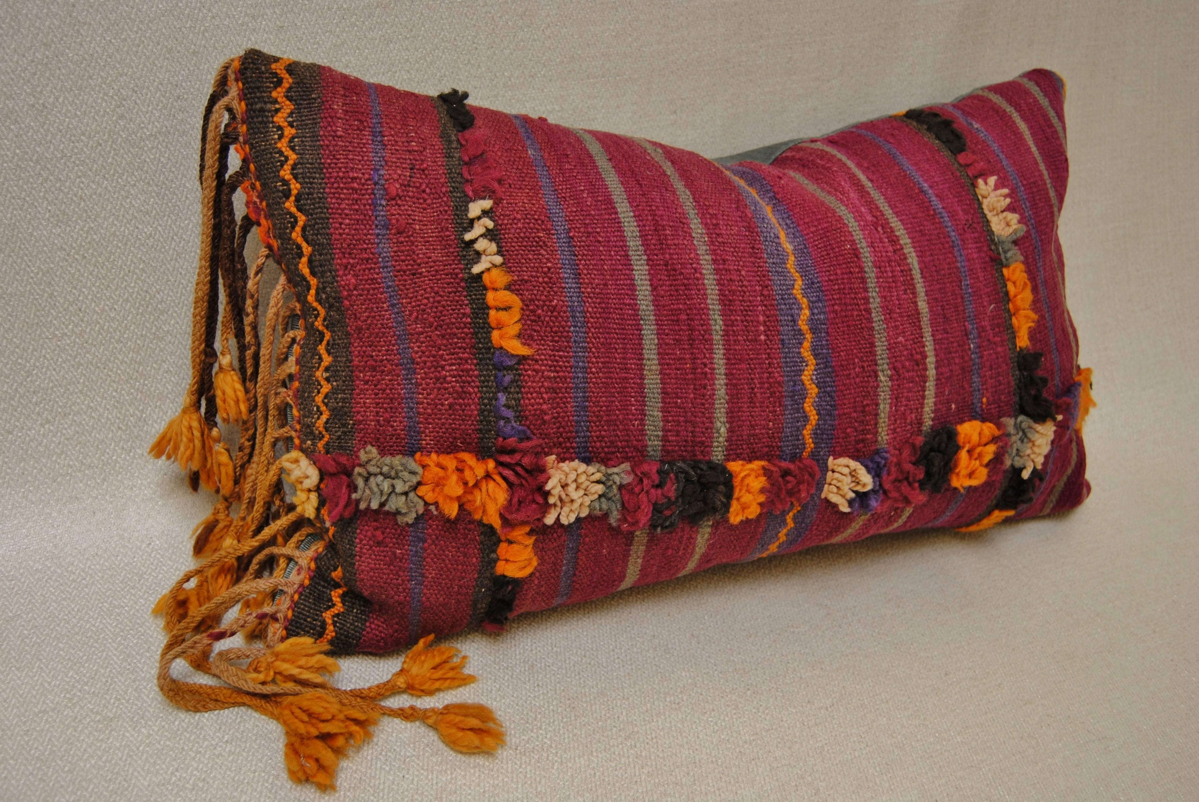 Custom pillow cut from a vintage hand loomed wool Moroccan Berber rug from the Atlas Mountains. Deep color stripes with tufted wool designs. The pillow incorporates the original long hand tied fringe that was on the one end of the textile. Pillow is