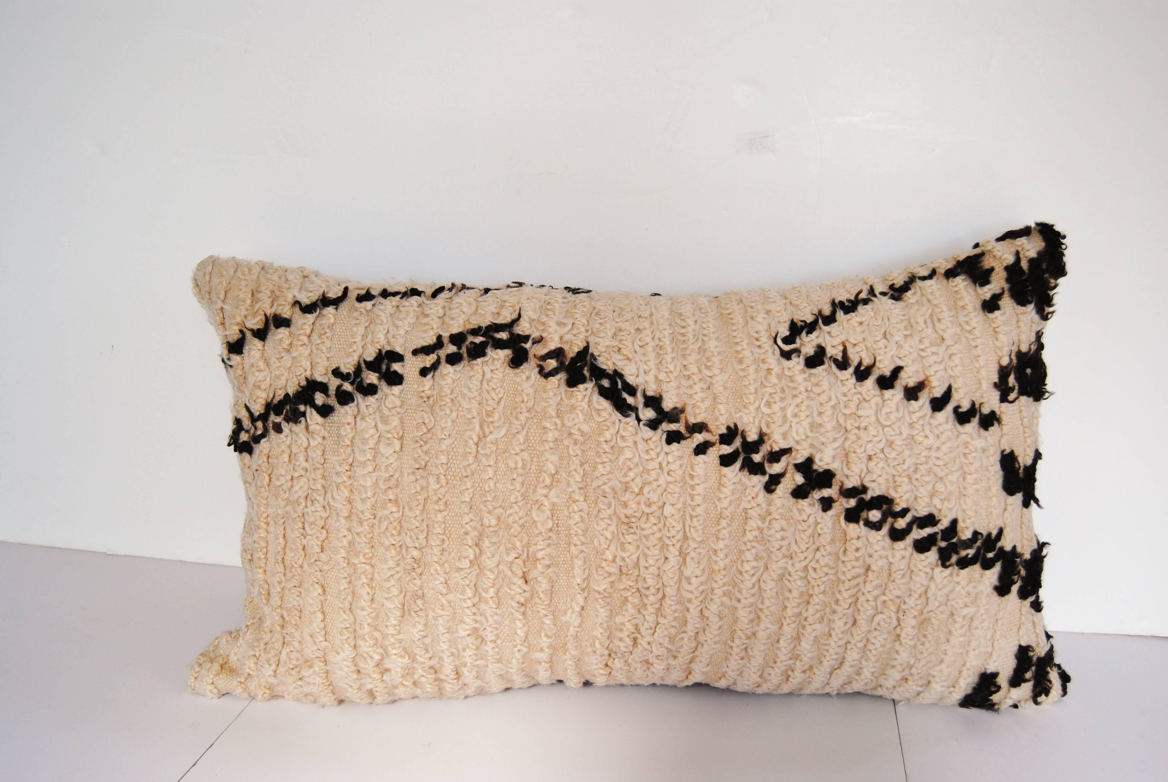 Custom pillow cut from a hand-loomed wool Moroccan Beni Ouarain rug from the Atlas Mountains. Wool is soft and lustrous in natural colors. Pillow is backed in a dark brown linen, filled with an insert of 50/50 down and feathers and hand-sewn closed.