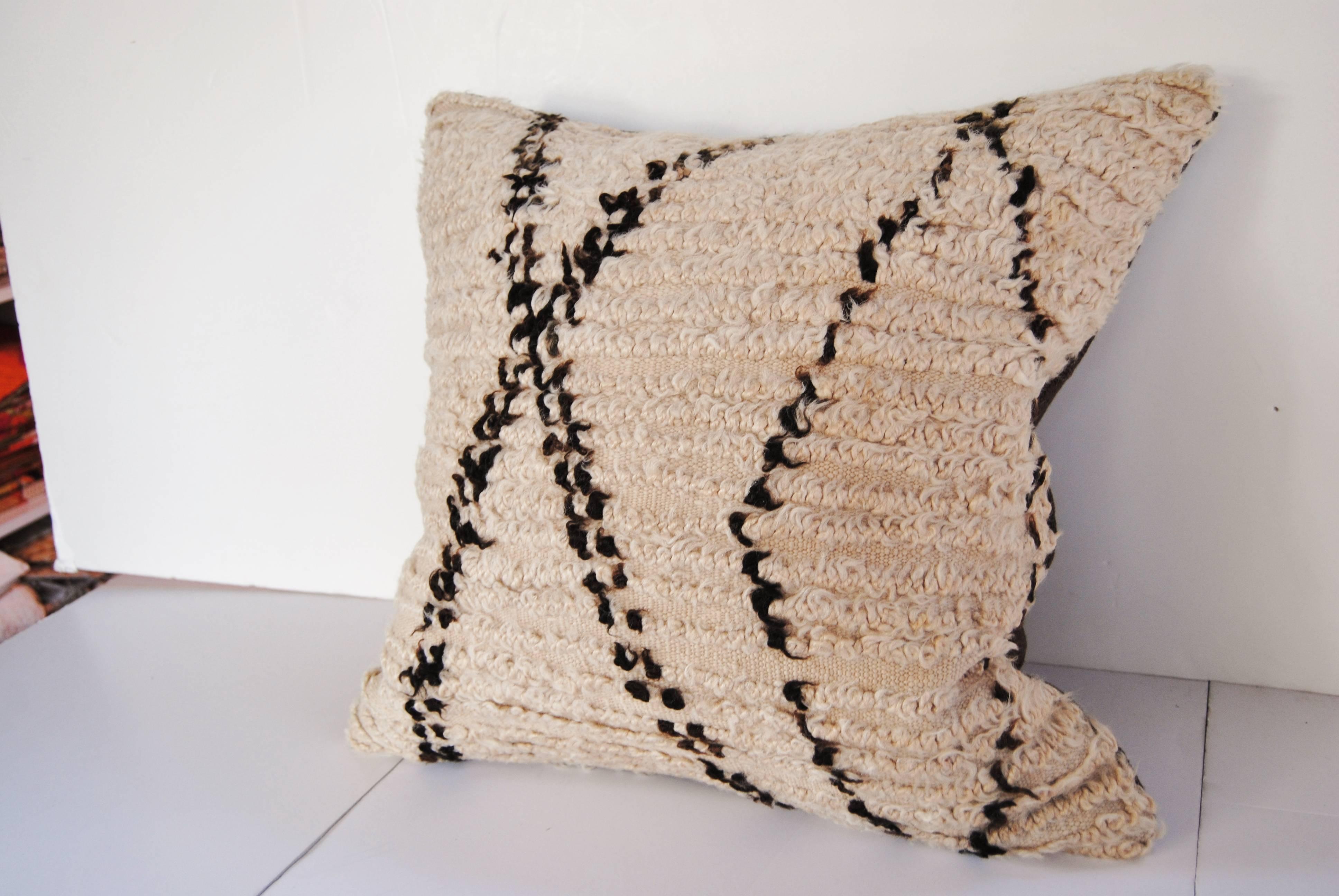 Custom pillow cut from a vintage hand-loomed wool Moroccan Beni Ouarain rug from the Atlas Mountains. Wool is soft and lustrous with natural color. Pillow is backed in dark brown linen, filled with an insert of 50/50 down and feathers and hand-sewn