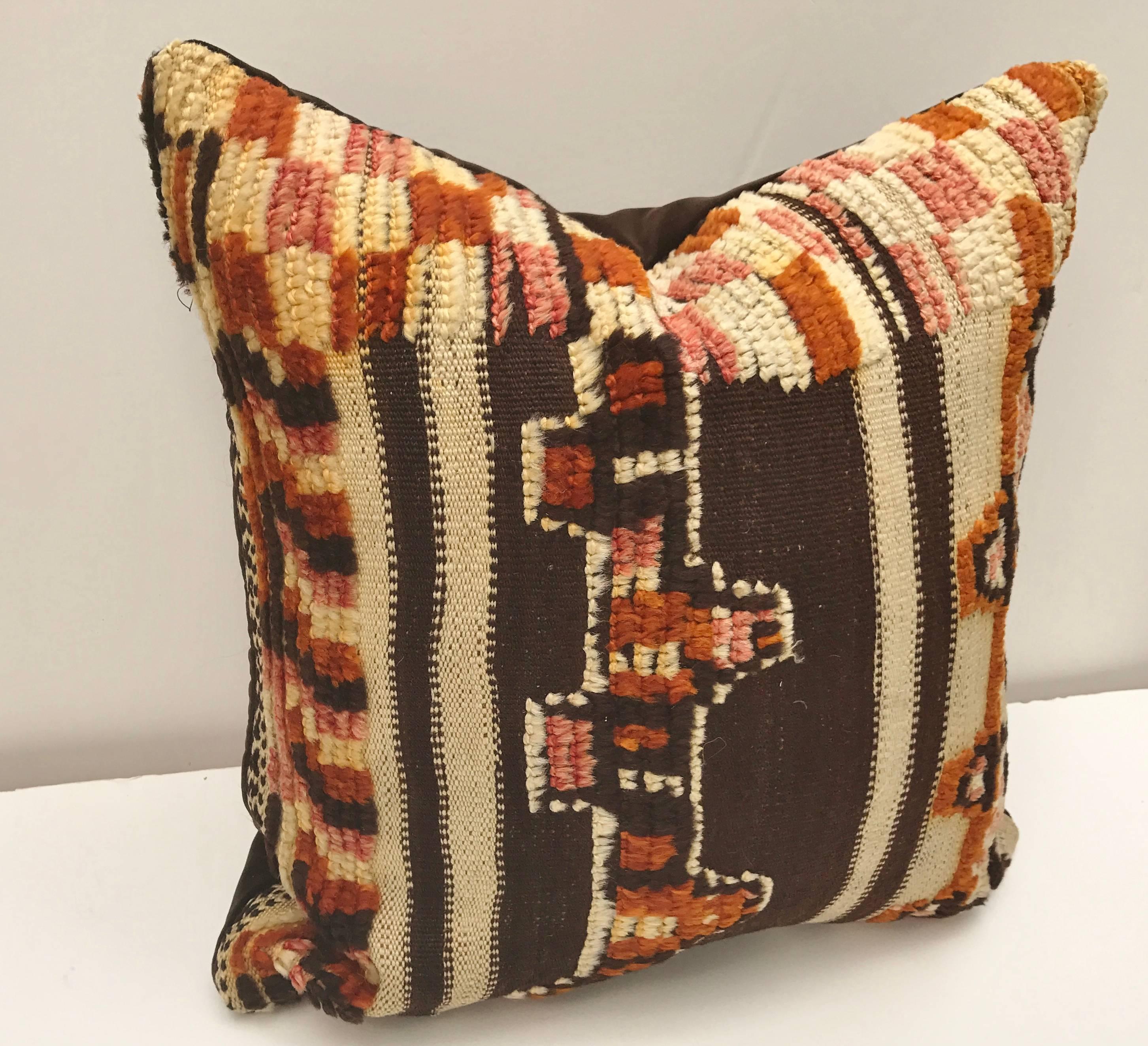 Custom pillow cut from a vintage hand loomed wool Moroccan Berber rug from the Atlas Mountains. Wool is soft and lustrous with good color. Flat-weave stripes are embellished with tufted tribal designs. Pillow is backed in dark brown velvet, filled