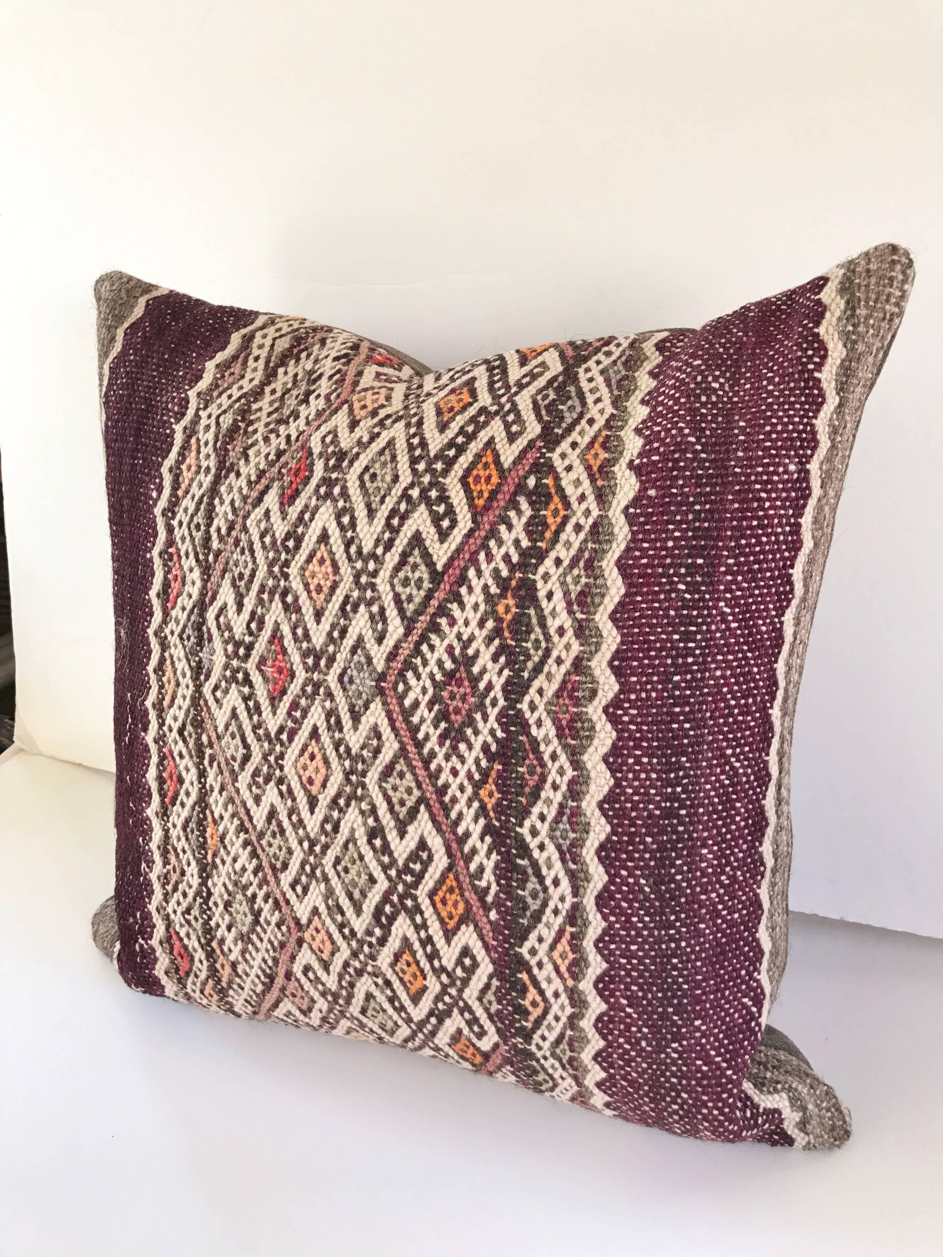Custom pillows cut from a vintage hand loomed wool Moroccan Berber rug from the Atlas Mountains. Color is all natural with bands of deep purple and multi colored tribal designs. Pillow is backed in a grey wool, filled with an insert of 50/50 down