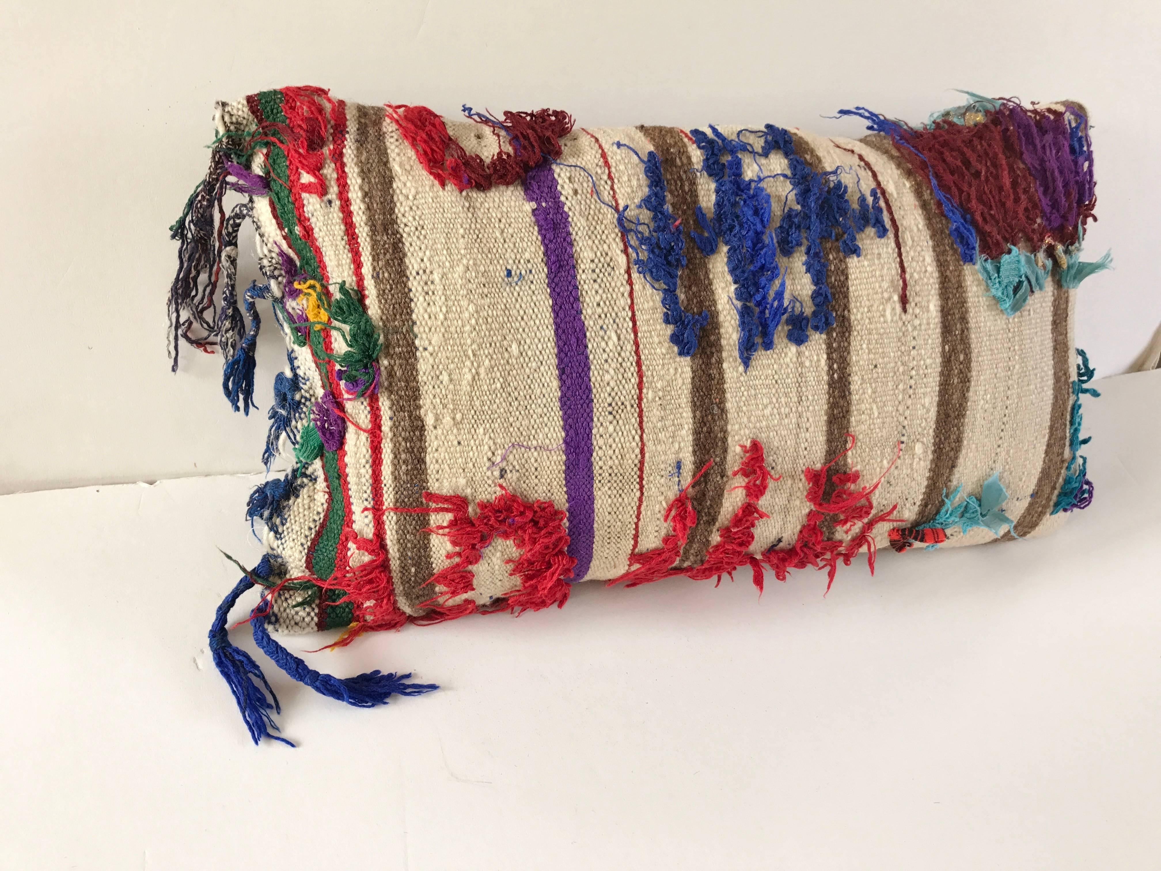 Custom pillow cut from a vintage hand loomed wool Moroccan rug from the Atlas Mountains.  Flat weave stripes are embellished with colorful tufted designs.  Pillow is backed in a linen blend, filled with an insert of 50/50 down and feathers and hand