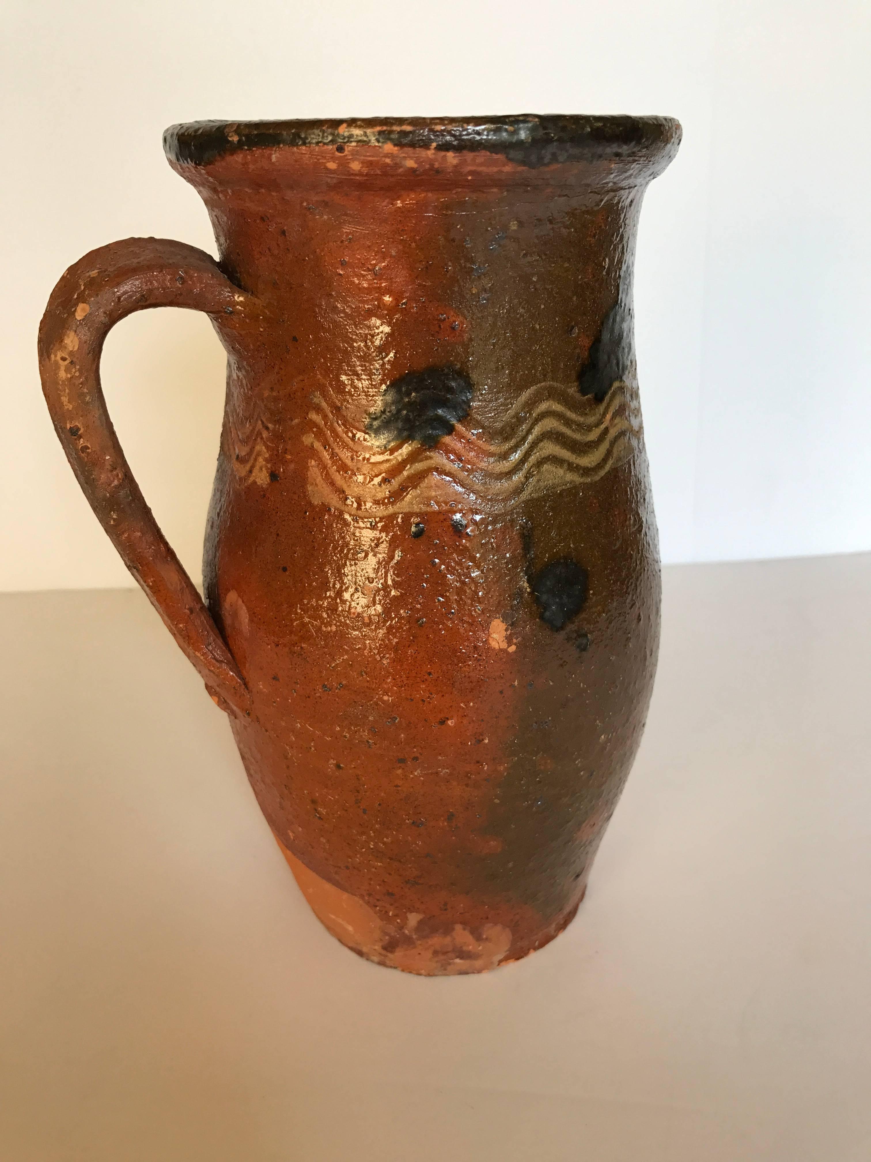 Vintage redware pitcher made in Transylvania, Romania, early 20th century. Pitcher still has a nice glaze with traditional Folk Art designs and minimal flaking. Great decorative piece.