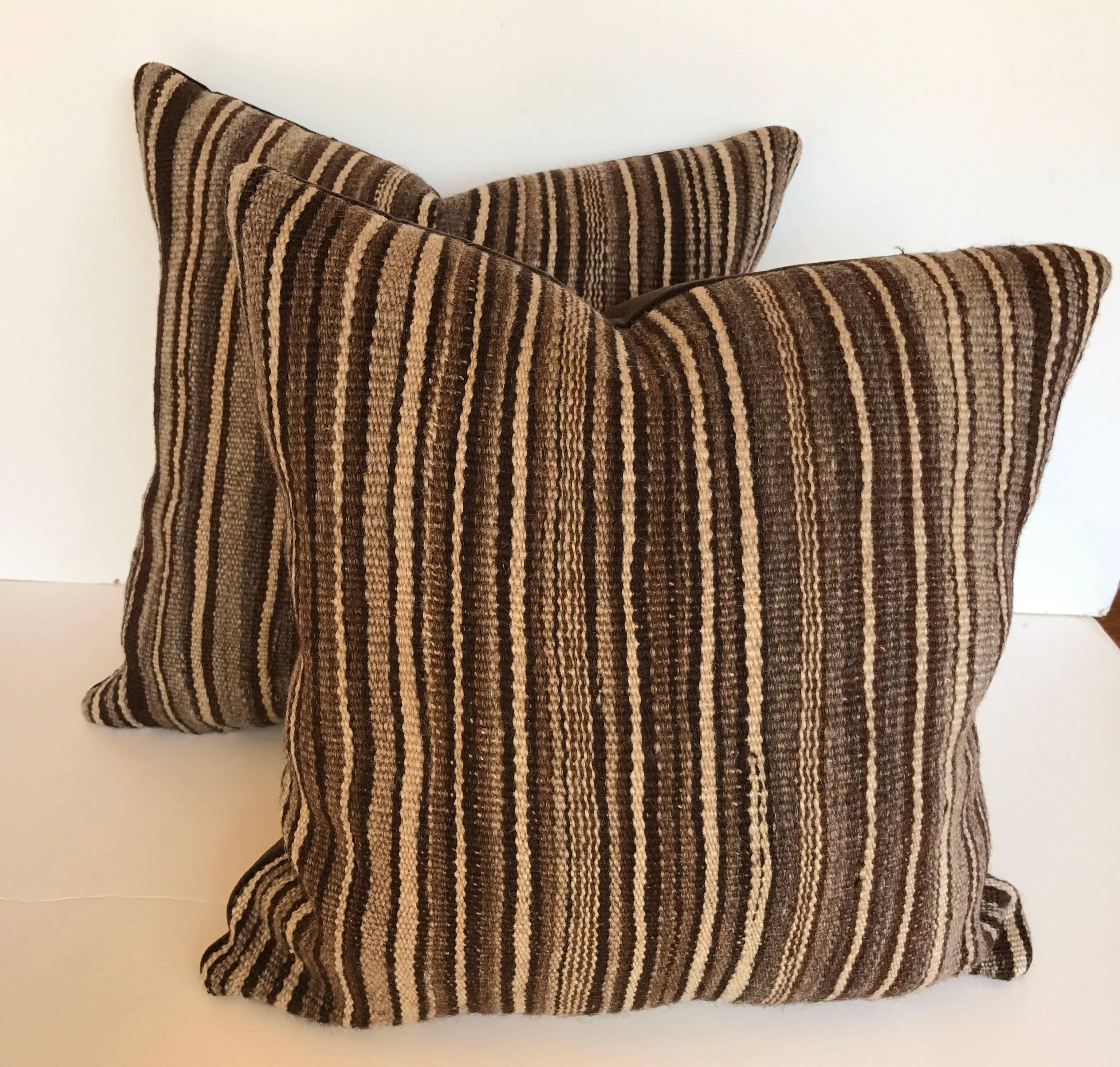 Custom pillows cut from a vintage hand loomed wool Moroccan Berber rug from the Atlas Mountains. Wool is soft and lustrous with stripes in natural colors of charcoal, grays, and brown. Pillows are backed in a dark brown velvet, filled with an inset