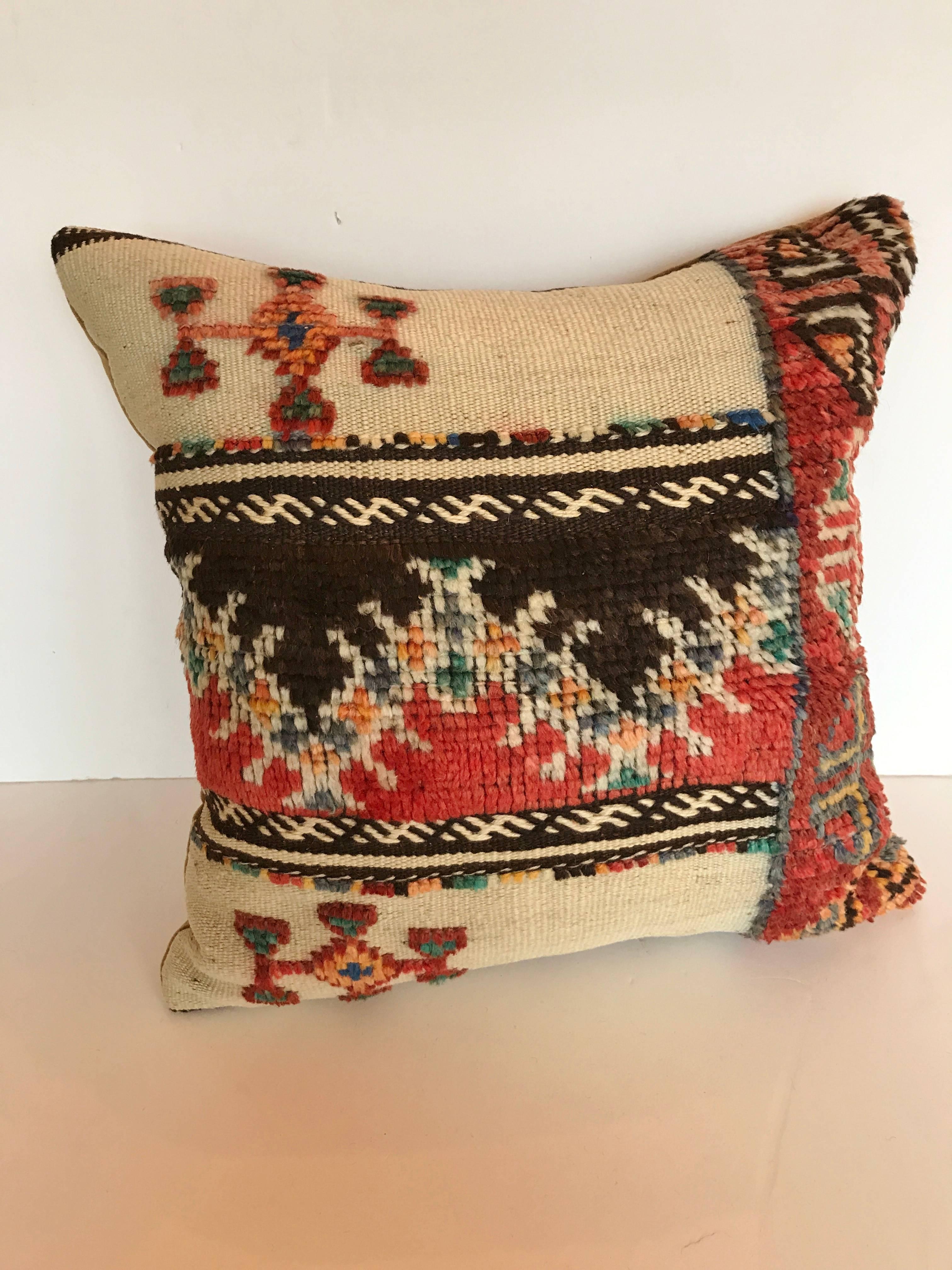 Custom pillow cut from a vintage hand loomed wool Moroccan rug made by the Berber tribes of the Atlas Mountains.  Wool is soft and lustrous with natural dyes.  Flat weave rug is embellished with woven tufted tribal designs.   Pillow is filled with