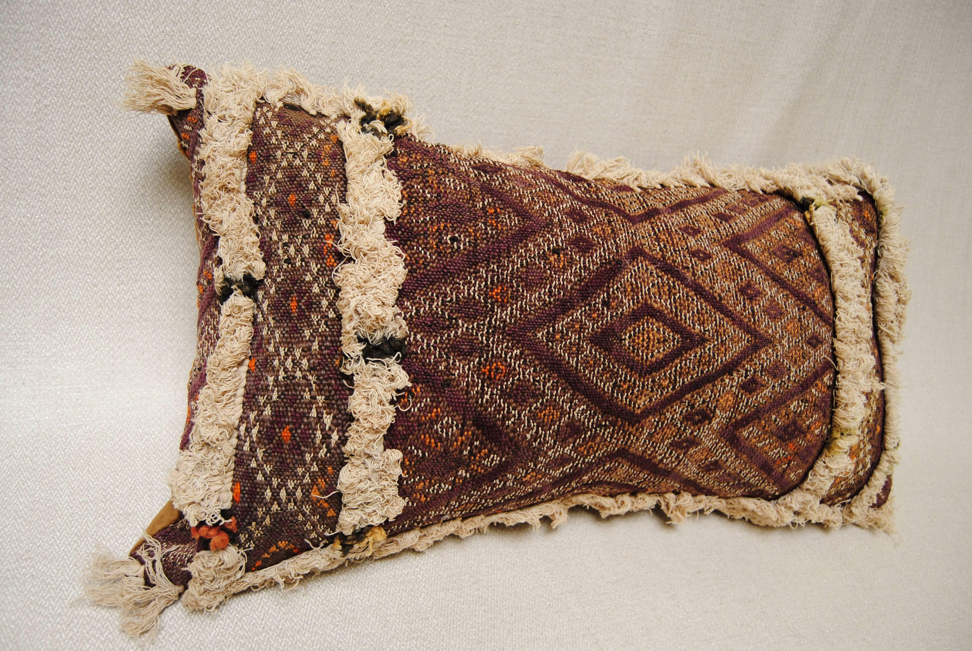 Custom pillow cut from a 100 yr. old hand loomed wool antique Moroccan rug from the Atlas Mountains. Each panel on the 20 foot long rug was a different design separated by ivory tufting. Rich color in purple, brown, orange and ivory. Pillow is