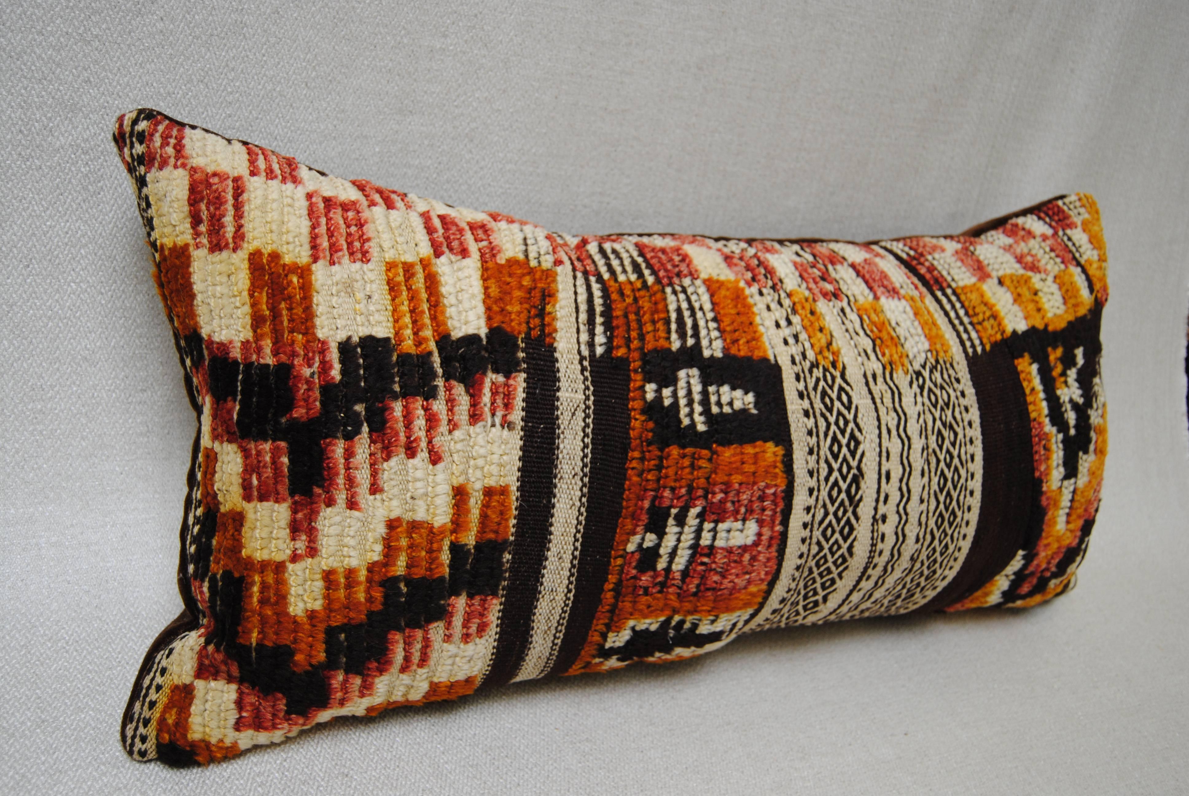 Custom pillow cut from a vintage hand-loomed wool Berber Moroccan rug from the Atlas Mountains. Wool is soft and lustrous with good natural color. The flat-weave is embellished with tufted designs. Pillow is backed in dark brown mohair, filled with