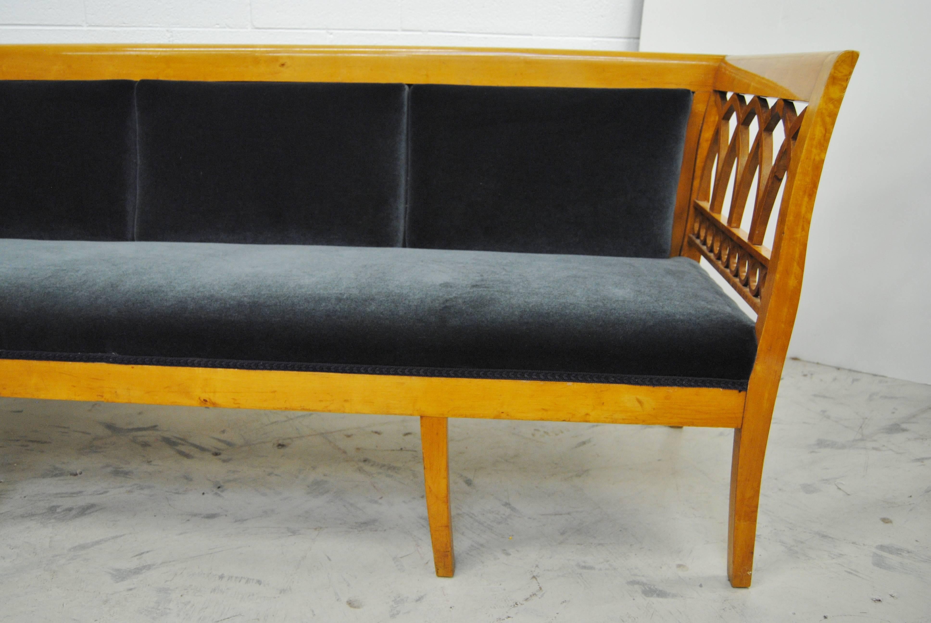 Antique Swedish Biedermeier settee, circa 1865, Beautiful lines with intricate openwork arm end panels. Minor loss of veneer on the inside of one arm, consistent with age of the piece. The settee is upholstered in a dark blue mohair, backed in