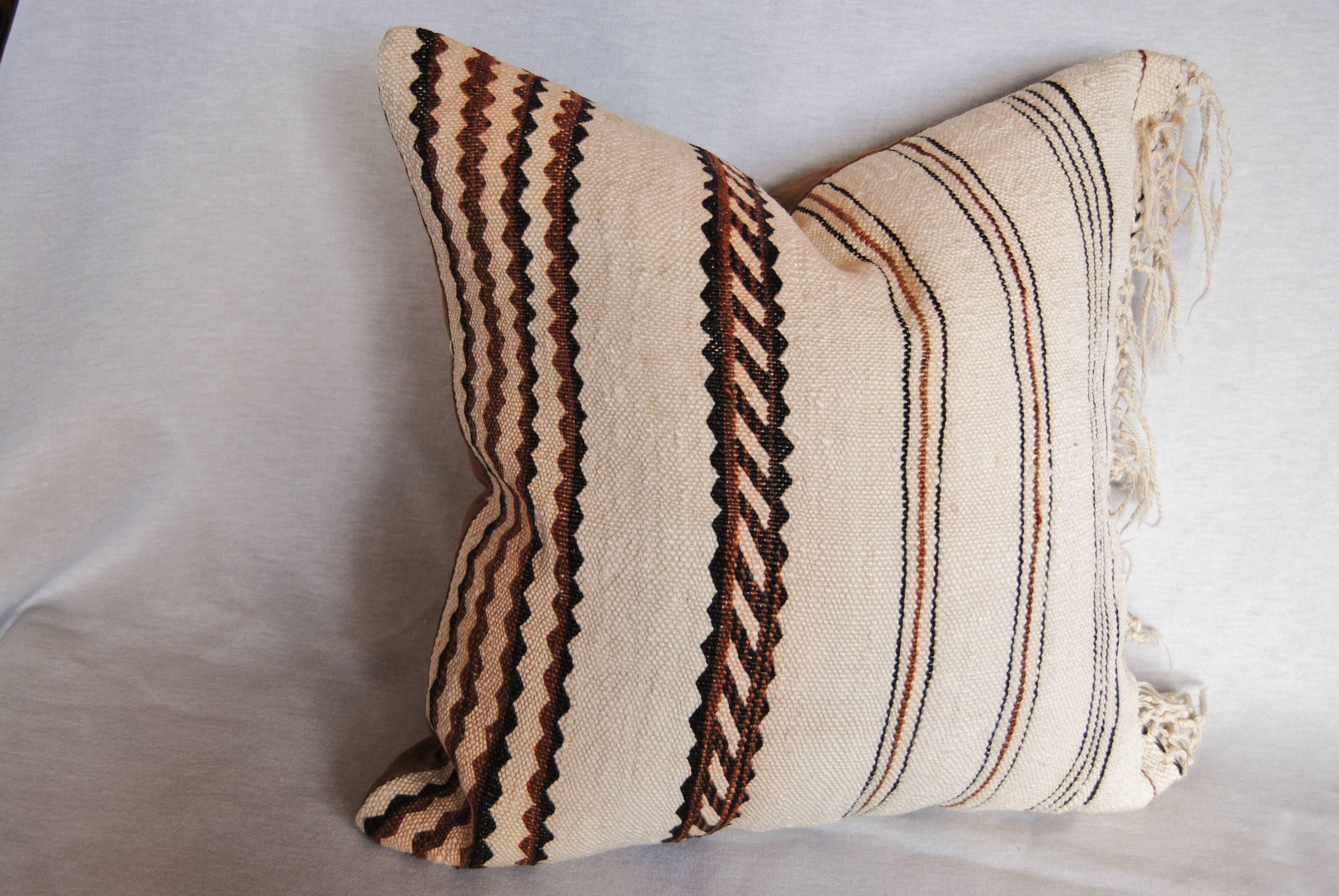 Custom pillow cut from a vintage hand loomed wool Moroccan Berber rug from the Atlas Mountains. The textile is soft and lustrous with natural color. The pillow is incorporates the original fringe from the rug, missing a few strands, but still in