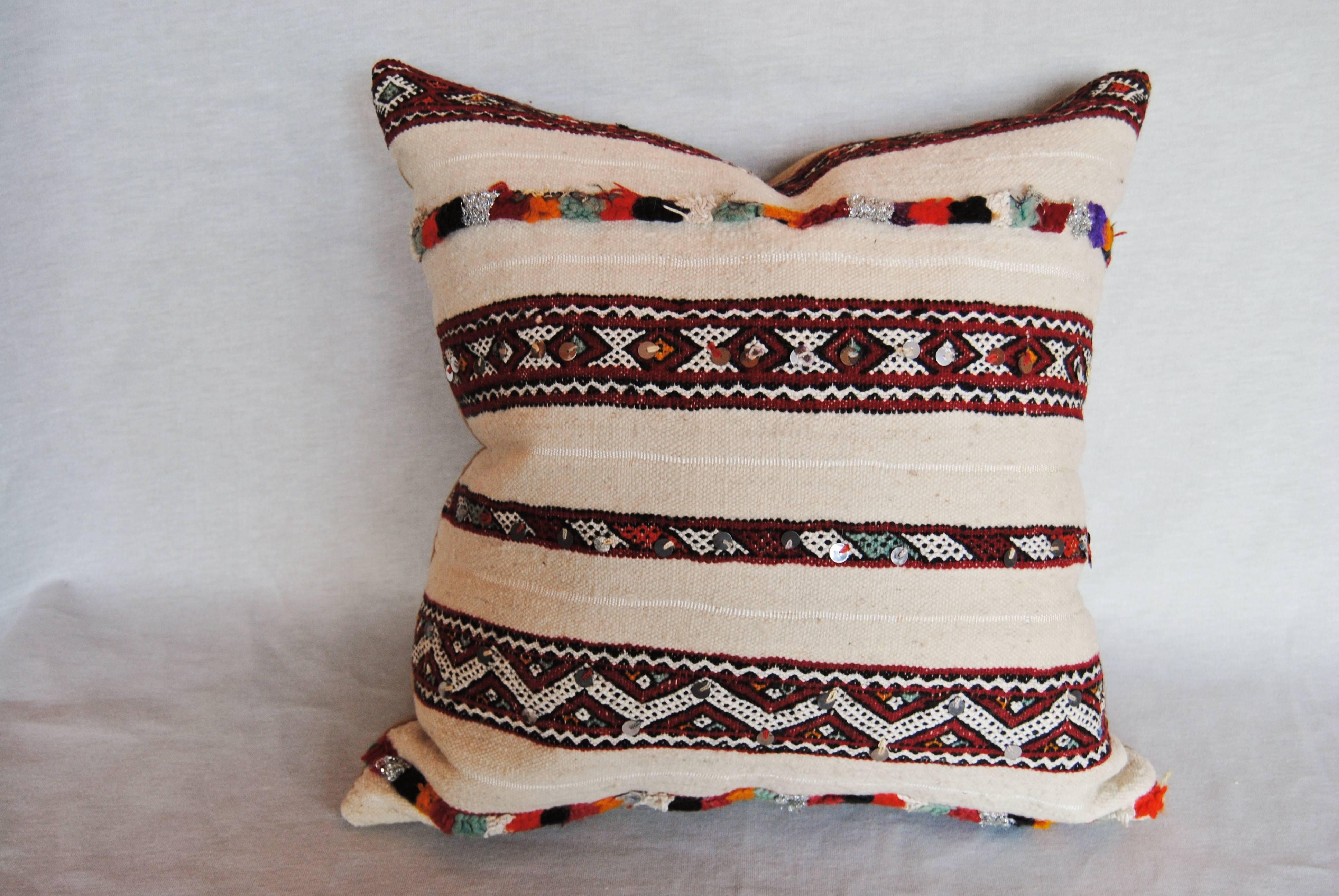 Custom Pillow Cut from a vintage hand loomed wool Moroccan rug  from the Atlas Mountains.  Flat weave stripes of the textile are embellished with colorful rows of tufted wool and sequins.  Wool is soft with good color.  Pillow is backed in a tan