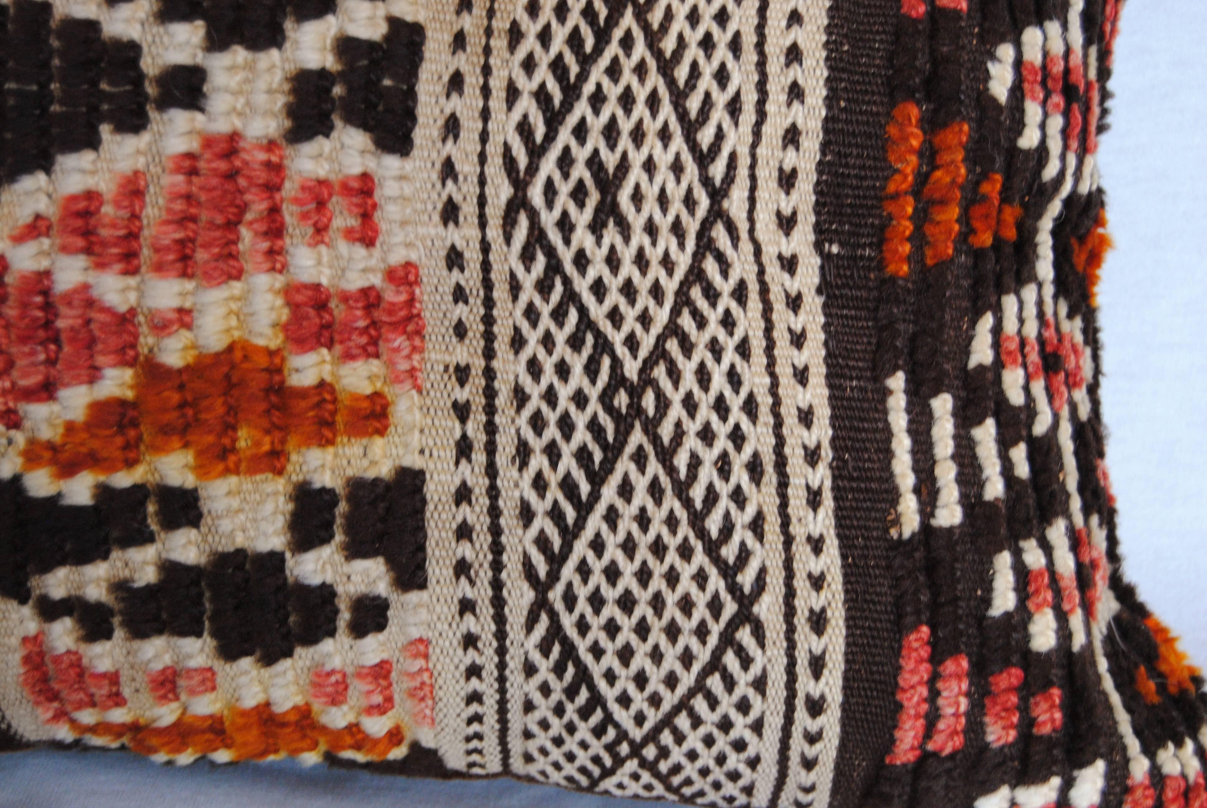 Custom pillow cut from a vintage hand loomed wool Moroccan Berber rug from the Atlas Mountains.  Flat weave stripes are embellished with raised wool tufting in tribal designs.  Wool is soft and lustrous with good natural color.  Pillow is backed in