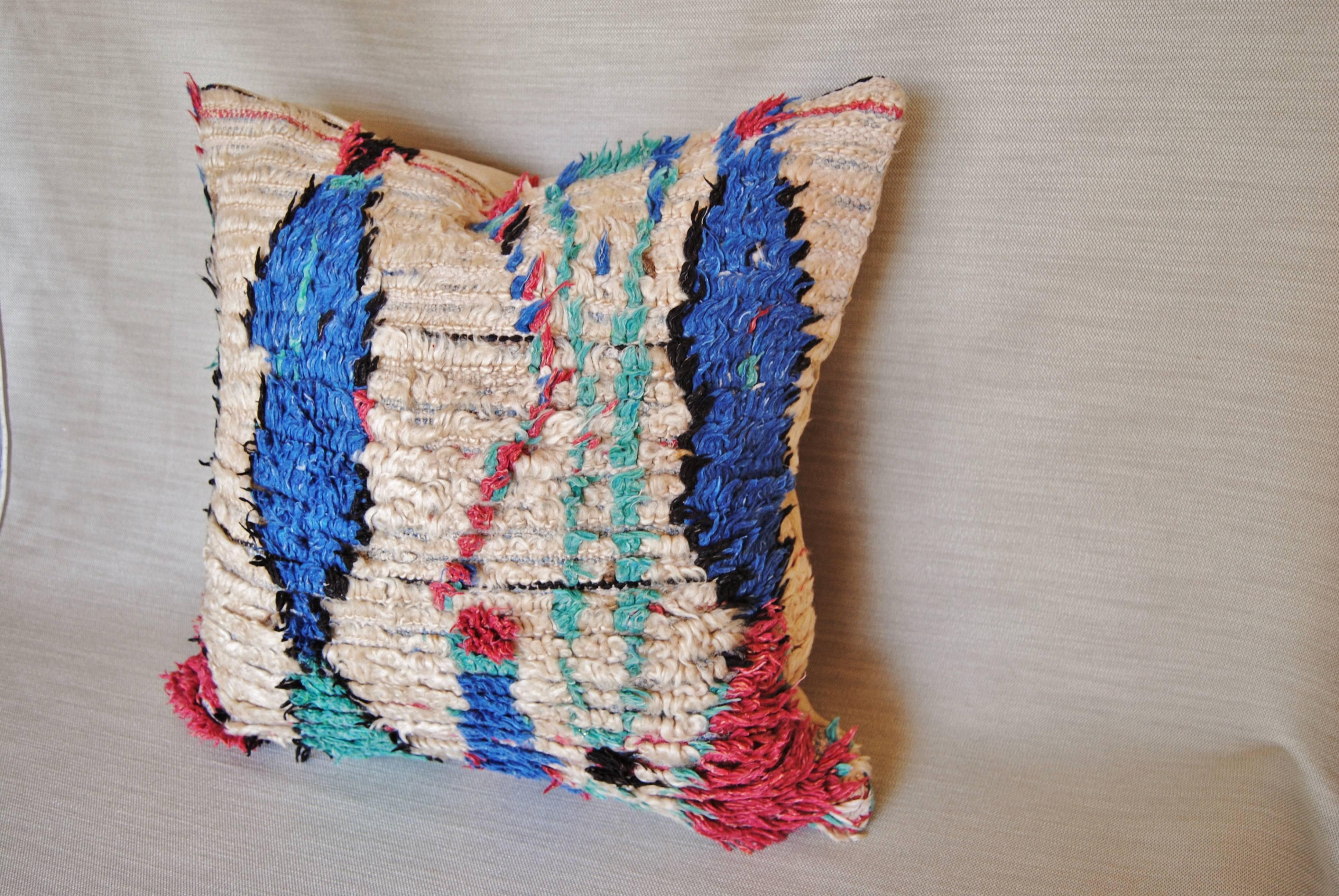 Custom pillow cut from a vintage hand loomed wool Moroccan Azilal rug from the Atlas Mountains. Textile has a soft hand and vividly colored tribal designs. Pillow is backed in a cream linen blend, filled with an insert of 50-50 down and feathers and