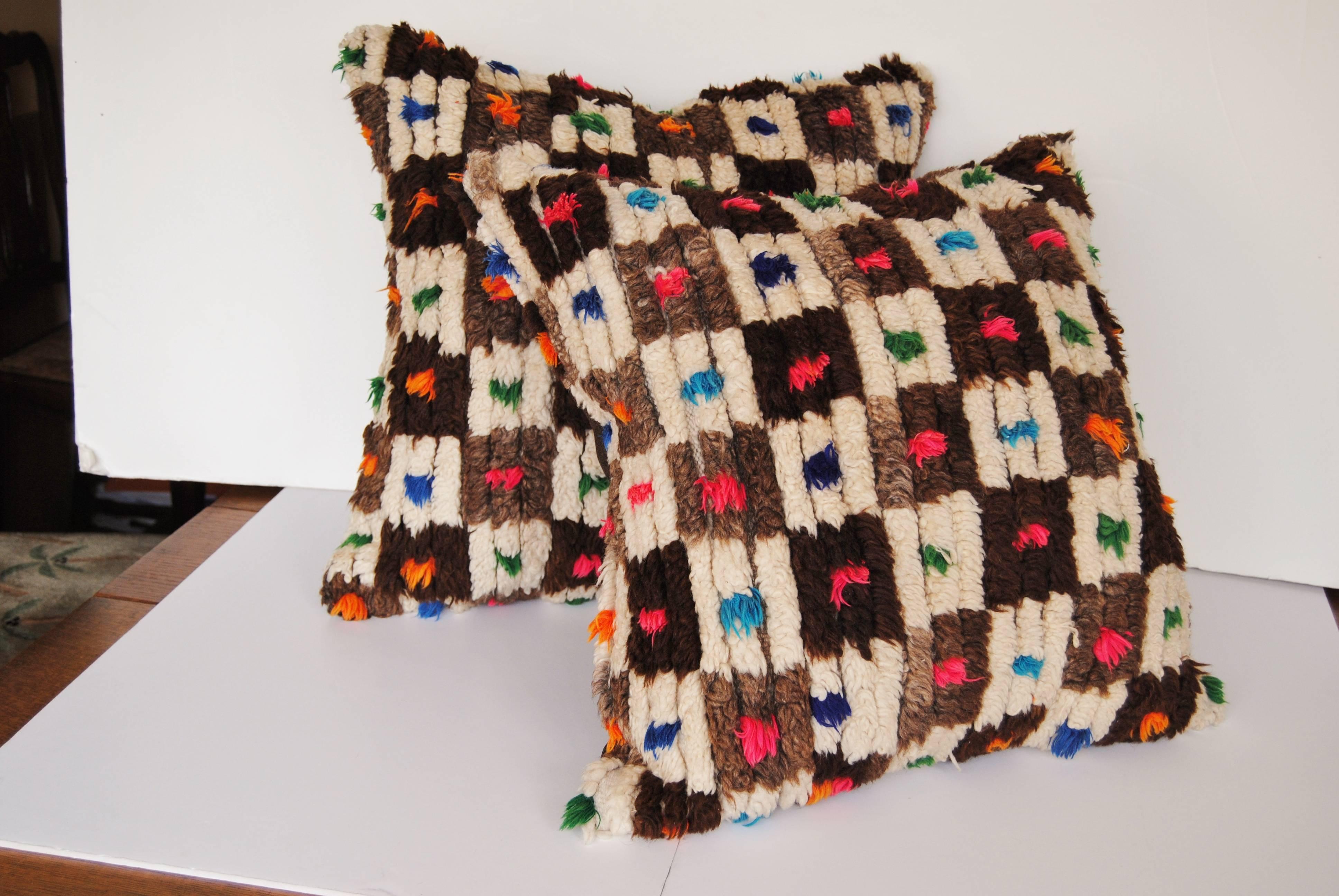 Custom pillow cut from a vintage hand loomed wool Moroccan Berber rug from the Atlas Mountains. Soft lustrous wool with natural colored squares and brightly colored tufts. Pillow is backed in a dark brown linen blend, filled with an insert of 50/50
