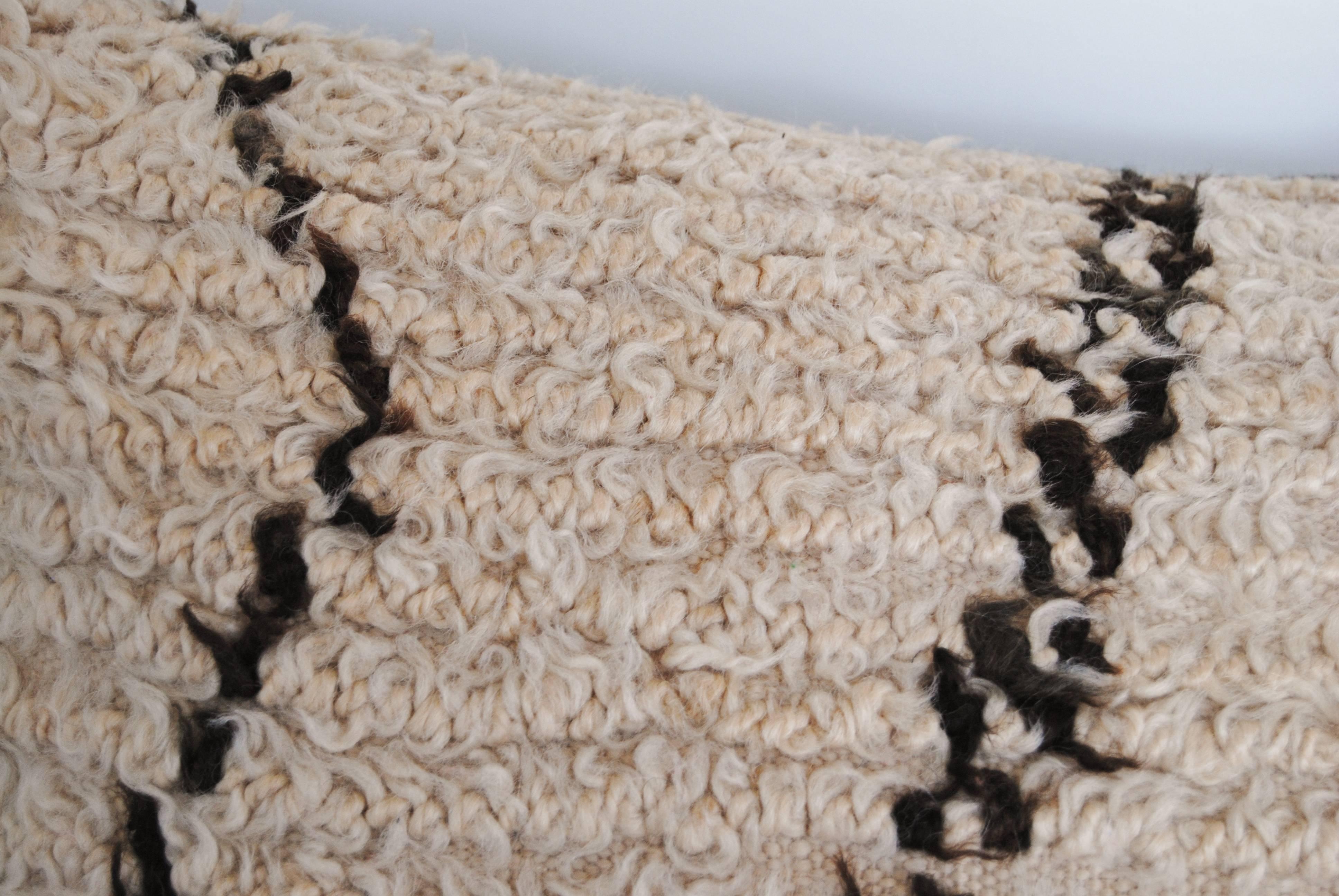 Custom pillow cut from a vintage hand loomed wool Moroccan rug from the Atlas Mountains.  Wool is soft and lustrous with natural color.  Pillow is backed in a dark brown linen, filled with an insert of 100% down  and hand sewn closed.