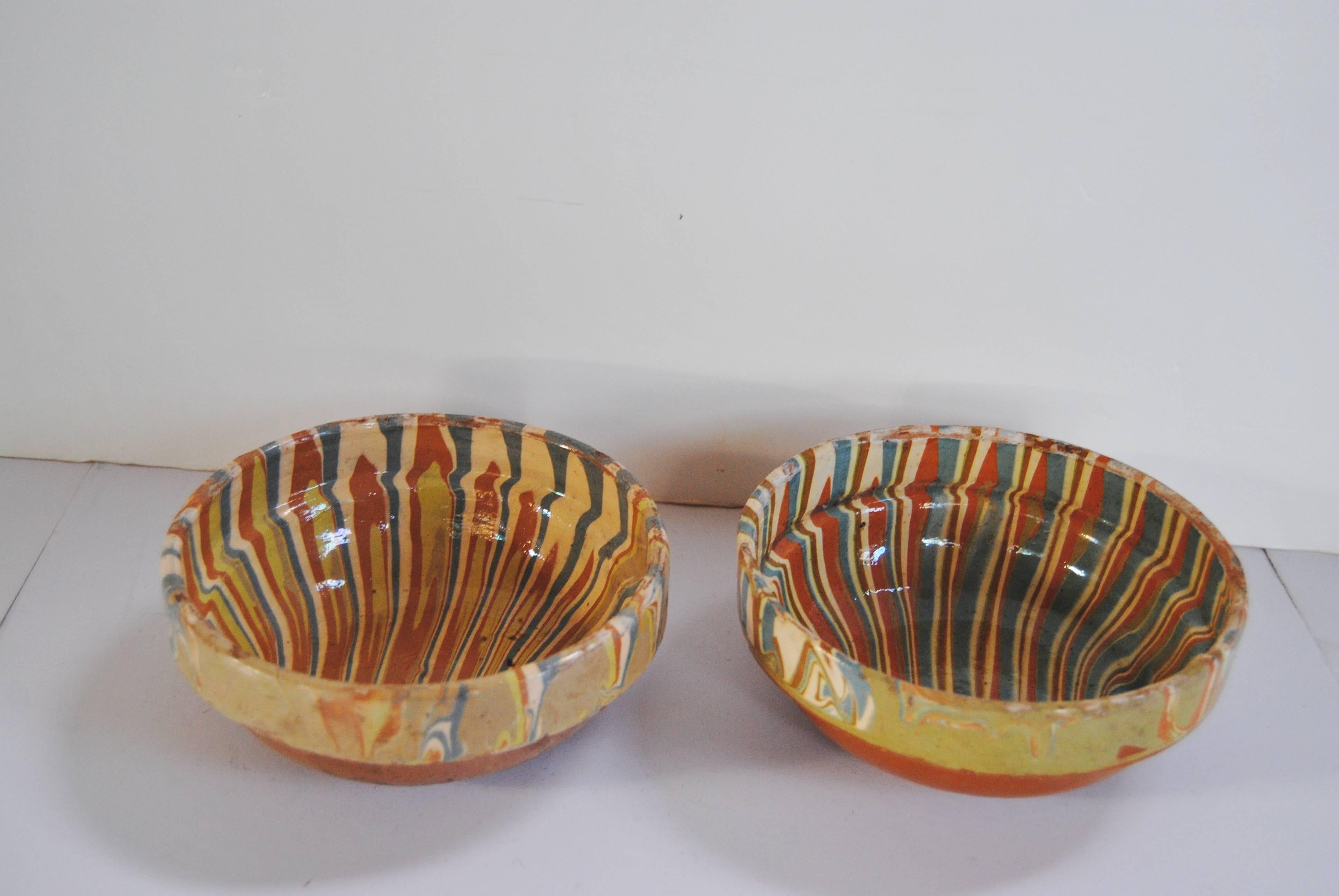 Hand thrown slipware pottery bowls from Transylvania, Romania. Made early 20th century, the pattern incorporates swirls of blue, green, cinnamon and dream similar to the French jaspe patterns. Minor wear on edges of bowls, consistent with use.