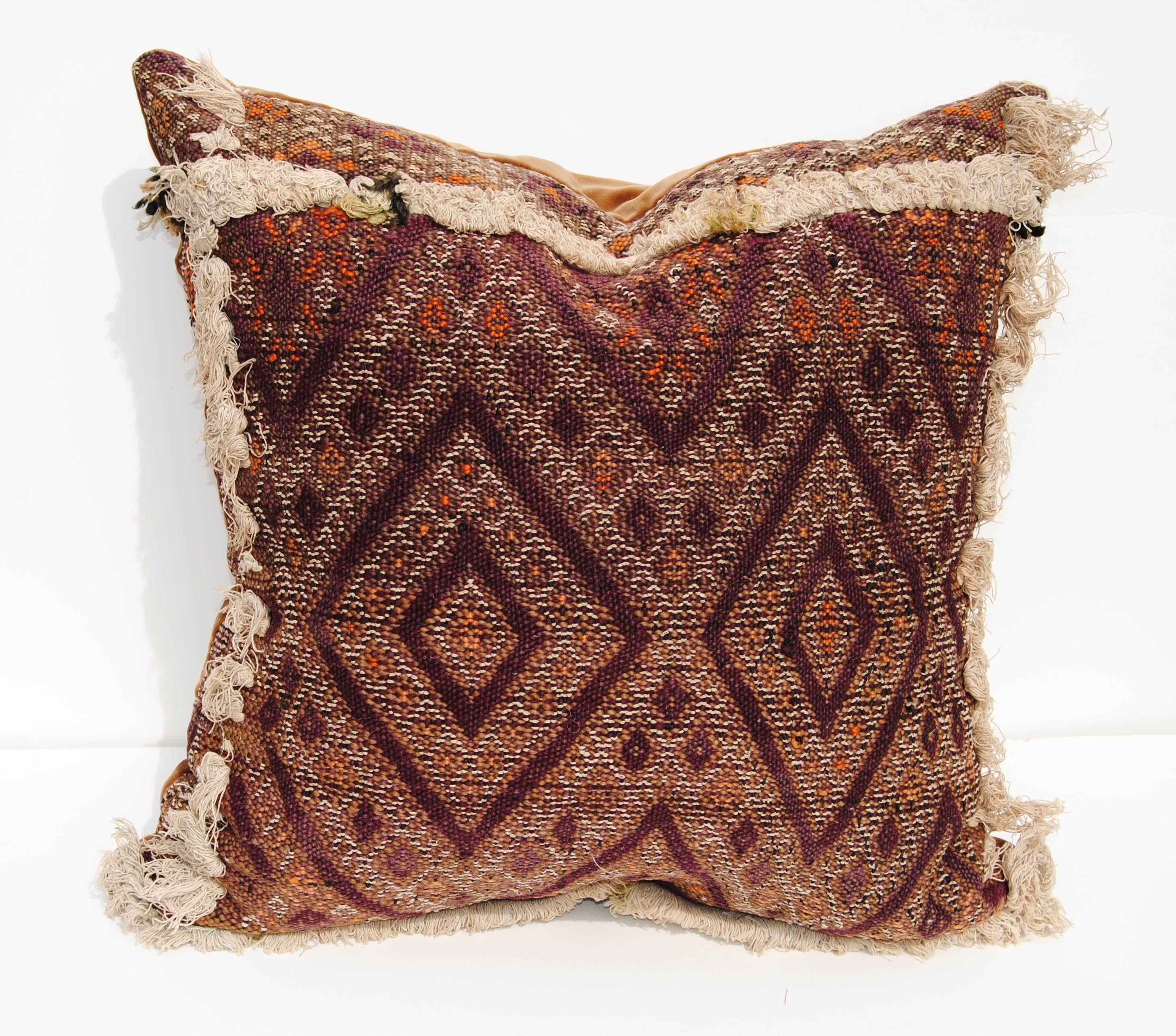 Custom pillow cut from an antique hand loomed wool Moroccan Berber rug from the Atlas mountains. The textile is about 100 years old and each panel was woven with a different tribal design with a hand tufted natural color cotton border. Rich natural