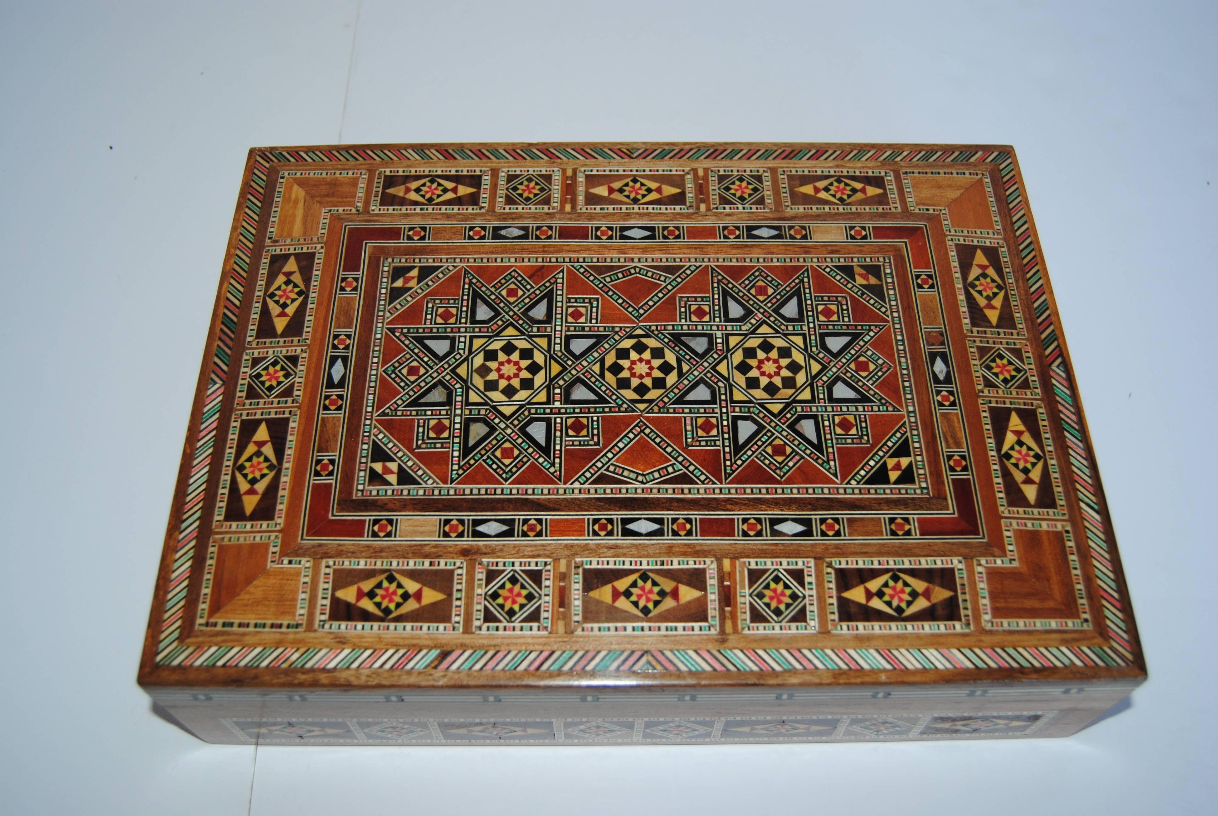 Syrian walnut wood box with different fruitwoods and mother-of-pearl. The top has a raised beveled edge with intricate inlay. It is lined with a wine velvet with four divided areas. Handmade by skilled Syrian artists in the late 20th century new